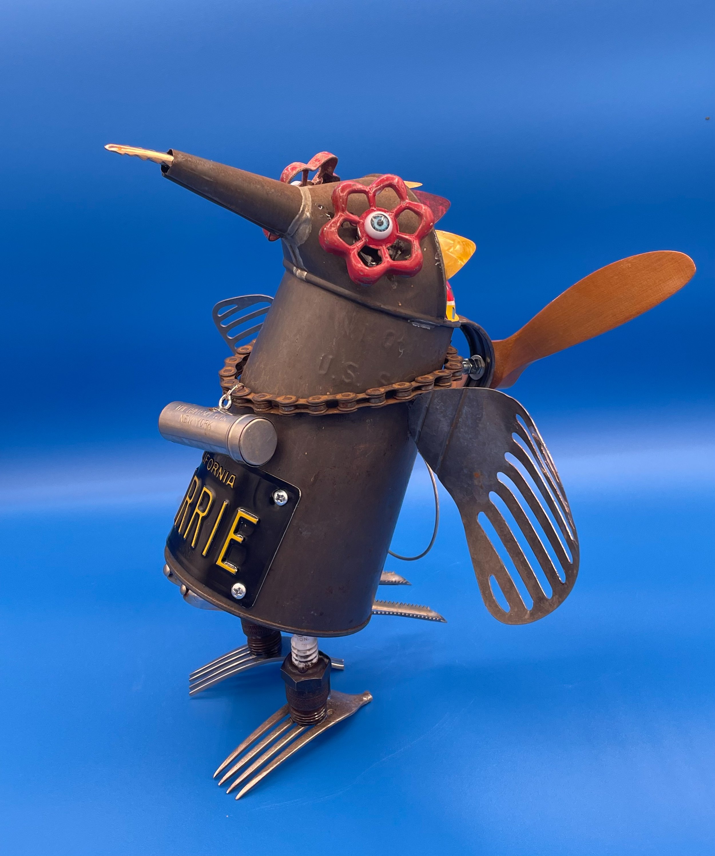 SOLD. Carrie R Pigeon, June 2022.
14"T X 10"W X 10"D.
Vintage oil pitcher, forks, spark plugs, vegetable peelers, metal spatulas, bicycle chain, dime bank, 1960 license plate, toy propeller, spigot handles, doll eyes, guitar pics.
Carrie was born