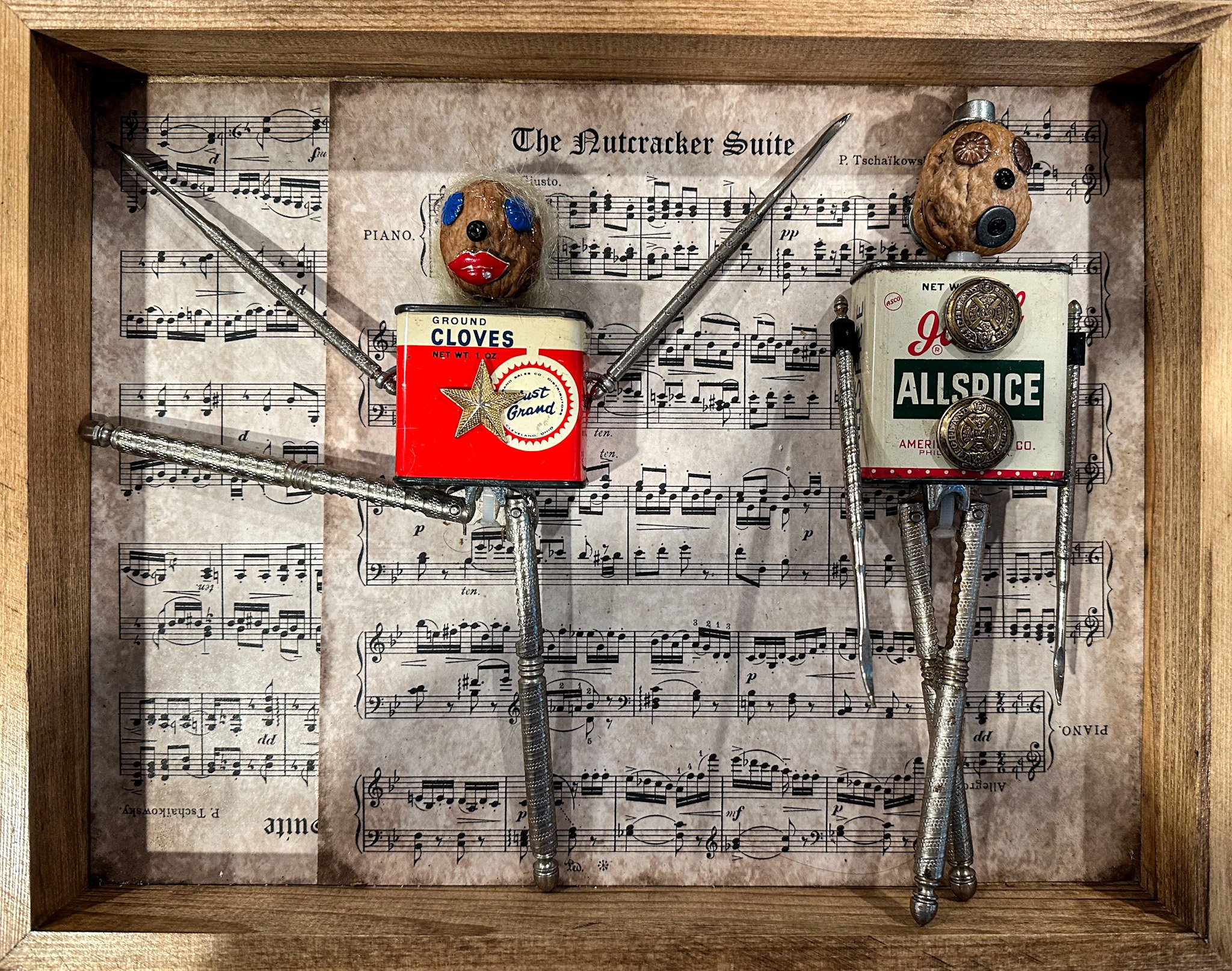 AVAILABLE. The Nutcracker Suite. 11" X 14" X 3".
Wooden frame, sheet music, vintage spice tins, steel nutcrackers, steel nut picks, vintage buttons, monopoly hat, furniture nails, hardware, charms, walnut shells (meat removed and shells boiled then r