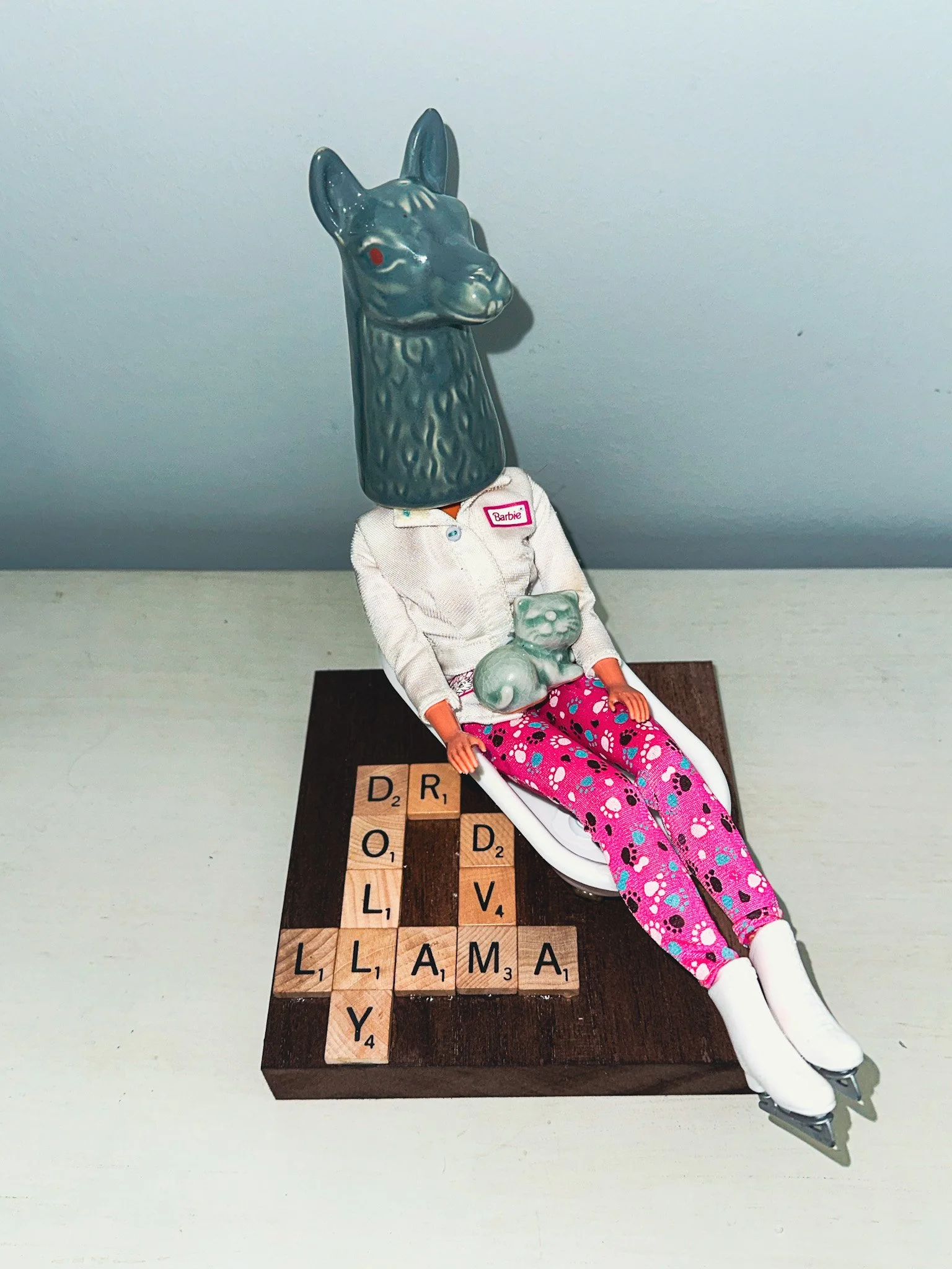 AVAILABLE: "Dr Dolly Llama DVM"
9" x 6" X 8"
Constructed from: Vet Barbie, pepper shaker, Celadon Green ceramic cat from Thailand, Scrabble tiles.