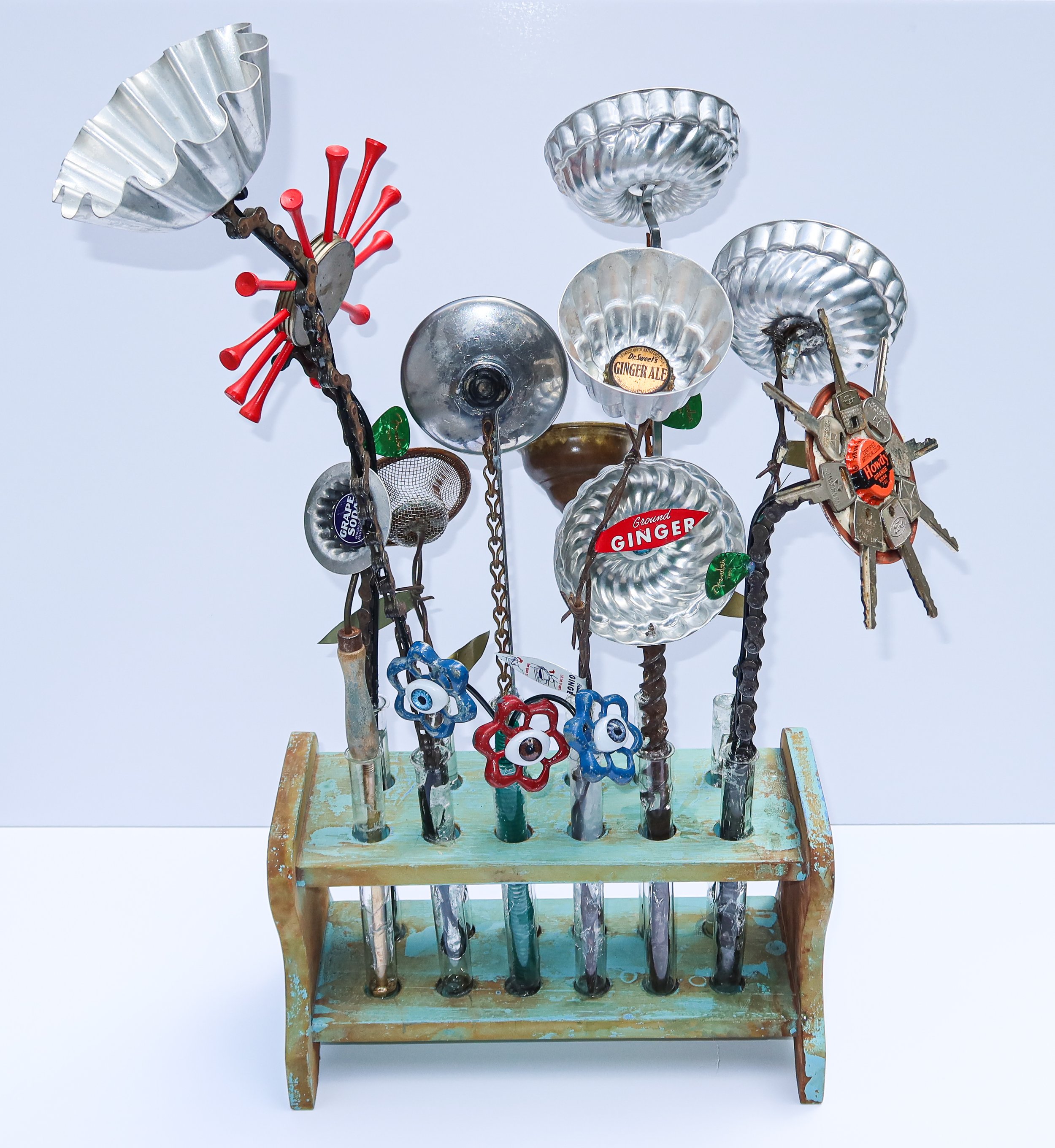 SOLD. The Flowers are Watching, view 1.
Vintage test tube rack, jello molds, baking dishes, spigot handles, doll eyes, old auto keys, golf tees, vintage soda caps, barbed wire, bicycle chain, sash chain.
14"W X 28"T X 12"D.