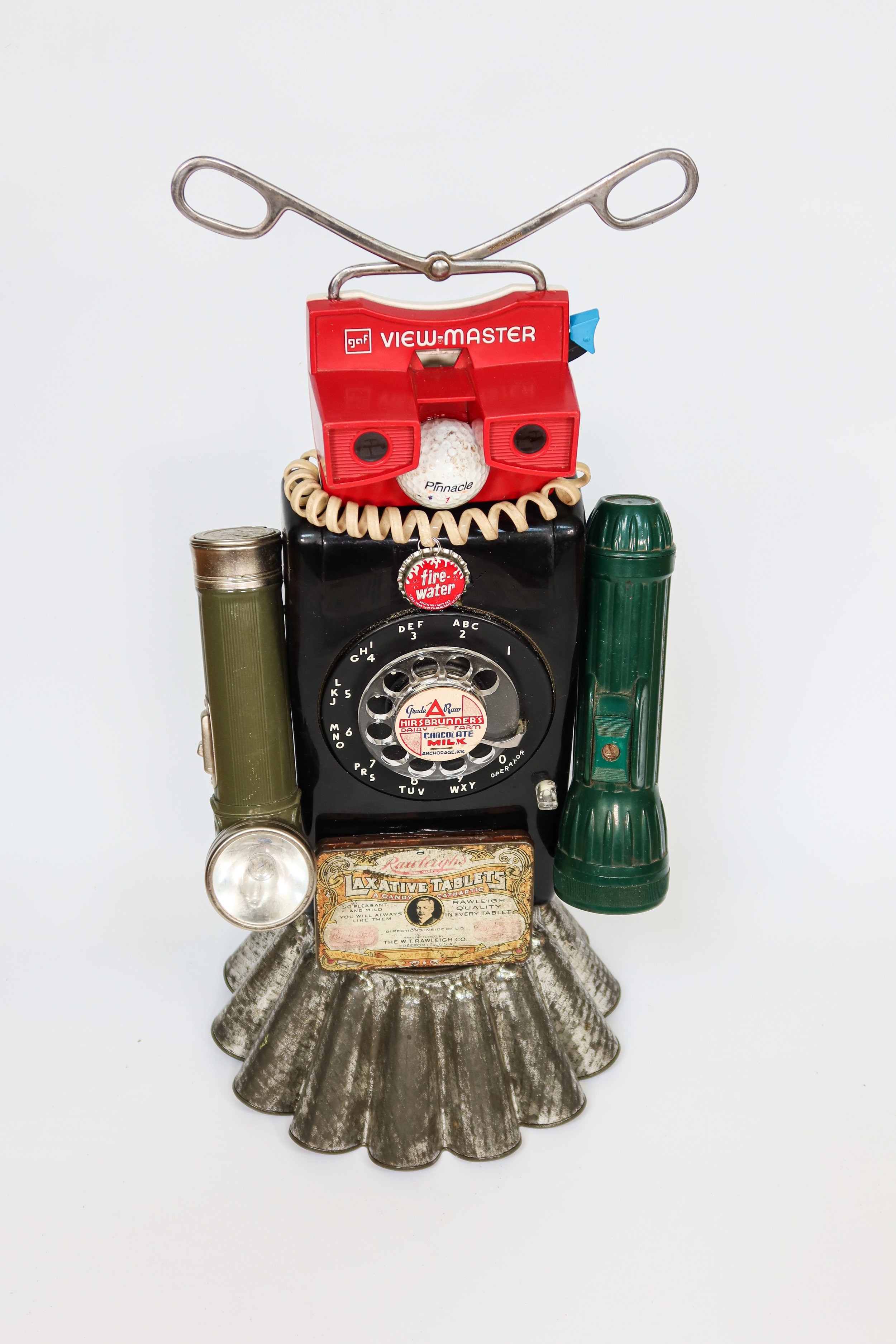 SOLD. Found Robot #1;
Viewmaster, ice tongs, vintage flashlights, wall telephone, milk lid, vintage tin, large jello mold.
20"T X 9"W X 9"D.