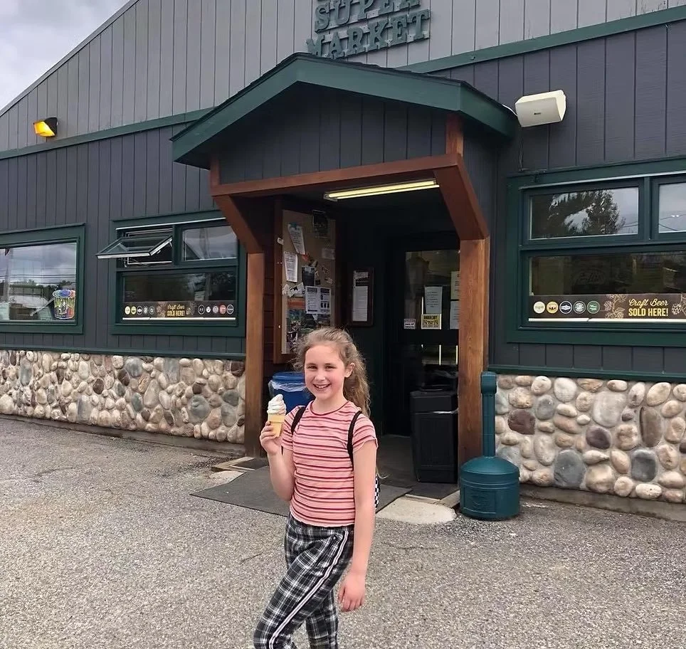 Happy girl in front of store with ice cream cone.
