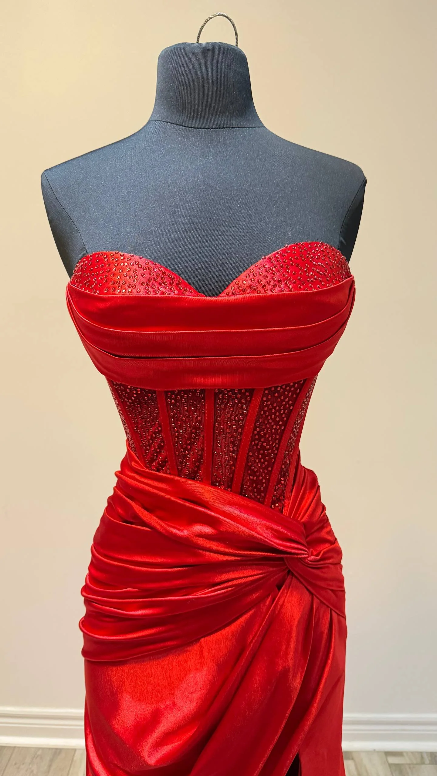 Red satin dress with beaded embellishments on the bust, displayed on a mannequin.