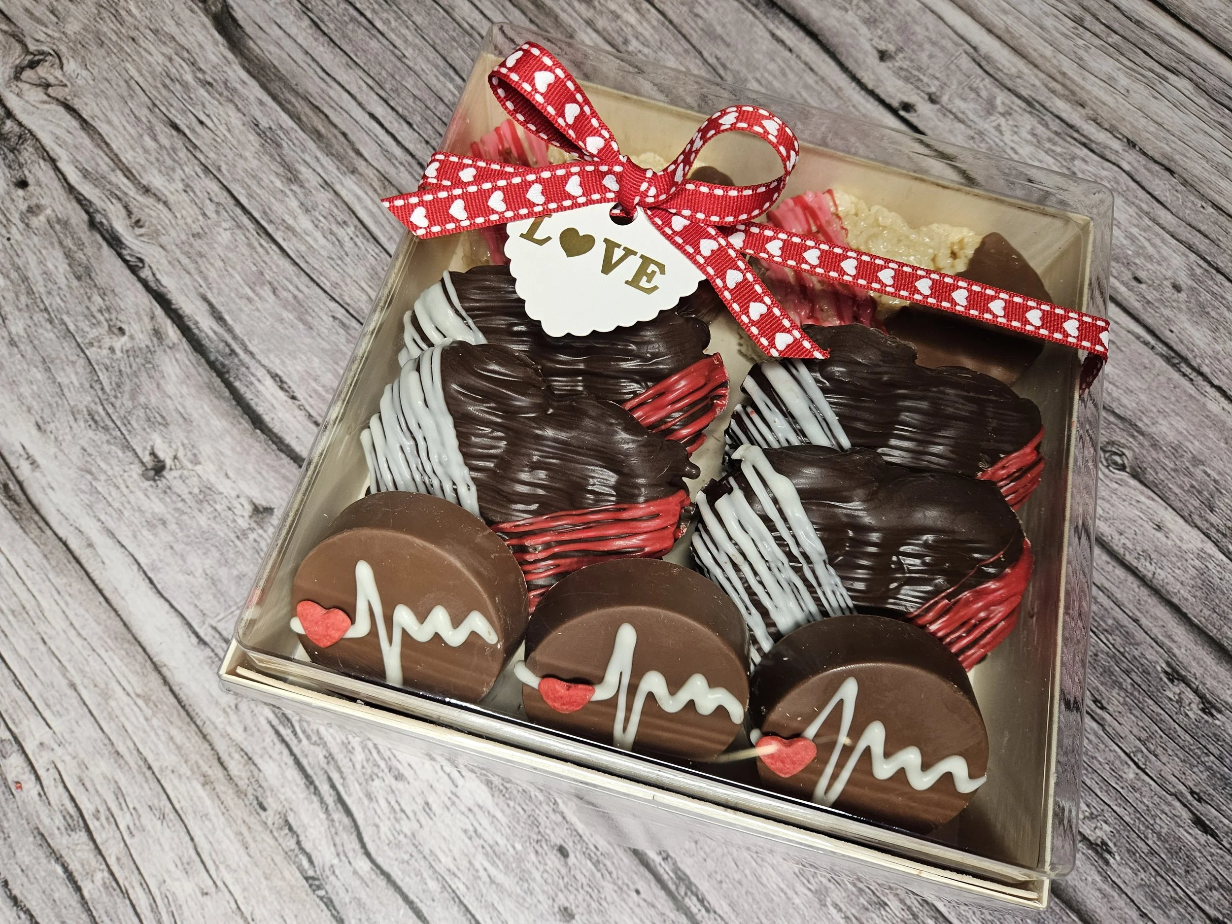 A gourmet goodie box filled with assorted chocolate-covered strawberries and chocolate-coated stuffed pretzels, decorated for spring including colorful drizzle, sprinkles and butterflies in a gift box with a 'Happy Easter' ribbon.