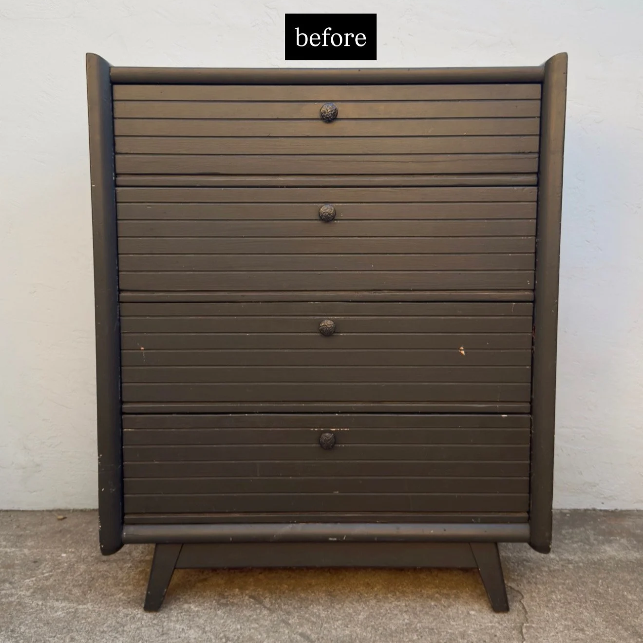 A brown wooden dresser with five drawers and round knobs, standing on four angled legs, placed outdoors on concrete ground against a wall, with a label reading 'before' at the top.