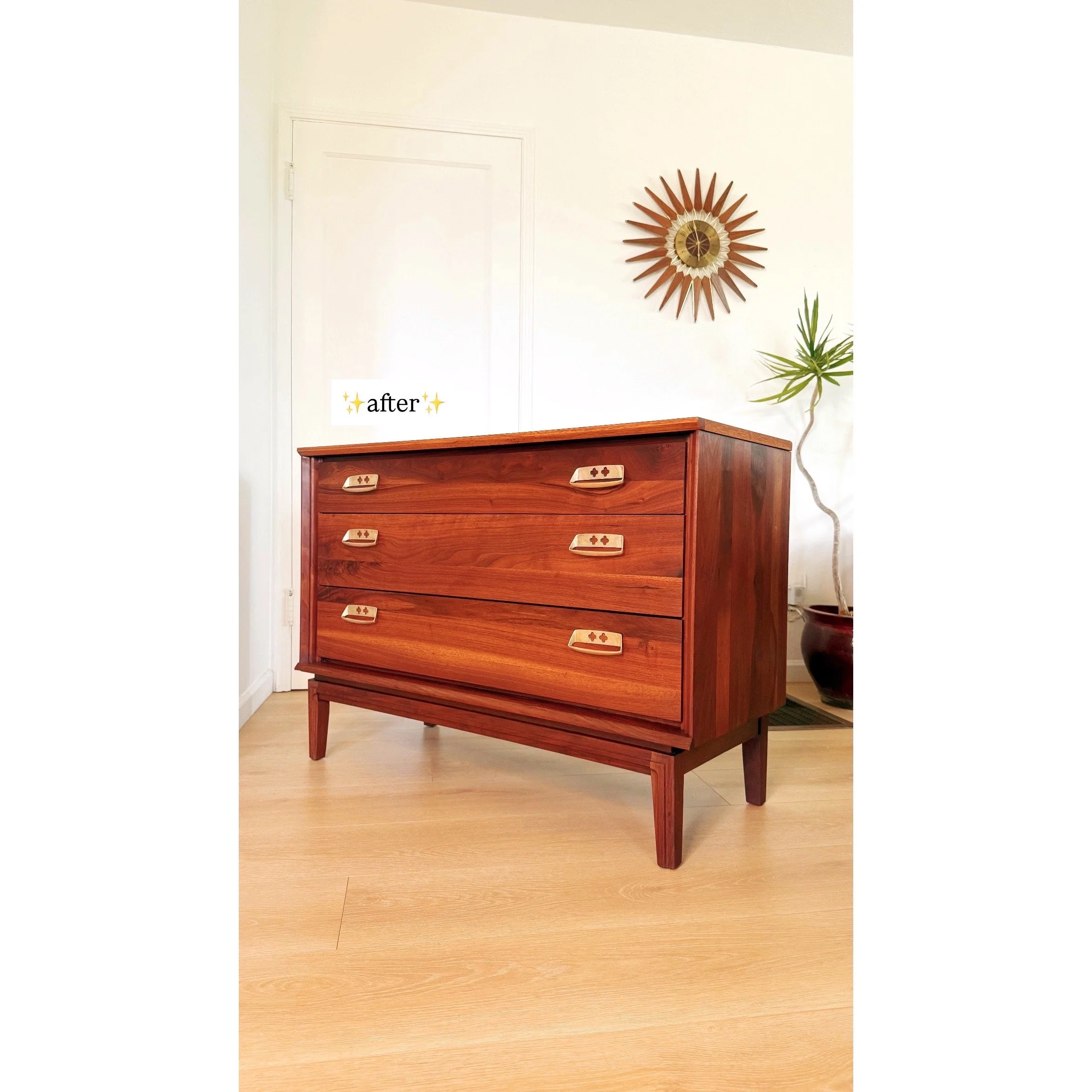 A wooden mid-century modern dresser with four drawers, placed on a light wood floor in a room with white walls. There is a wall clock with a sunburst design and a tall potted plant in the background. An 'after' sticker is on the top left of the dress