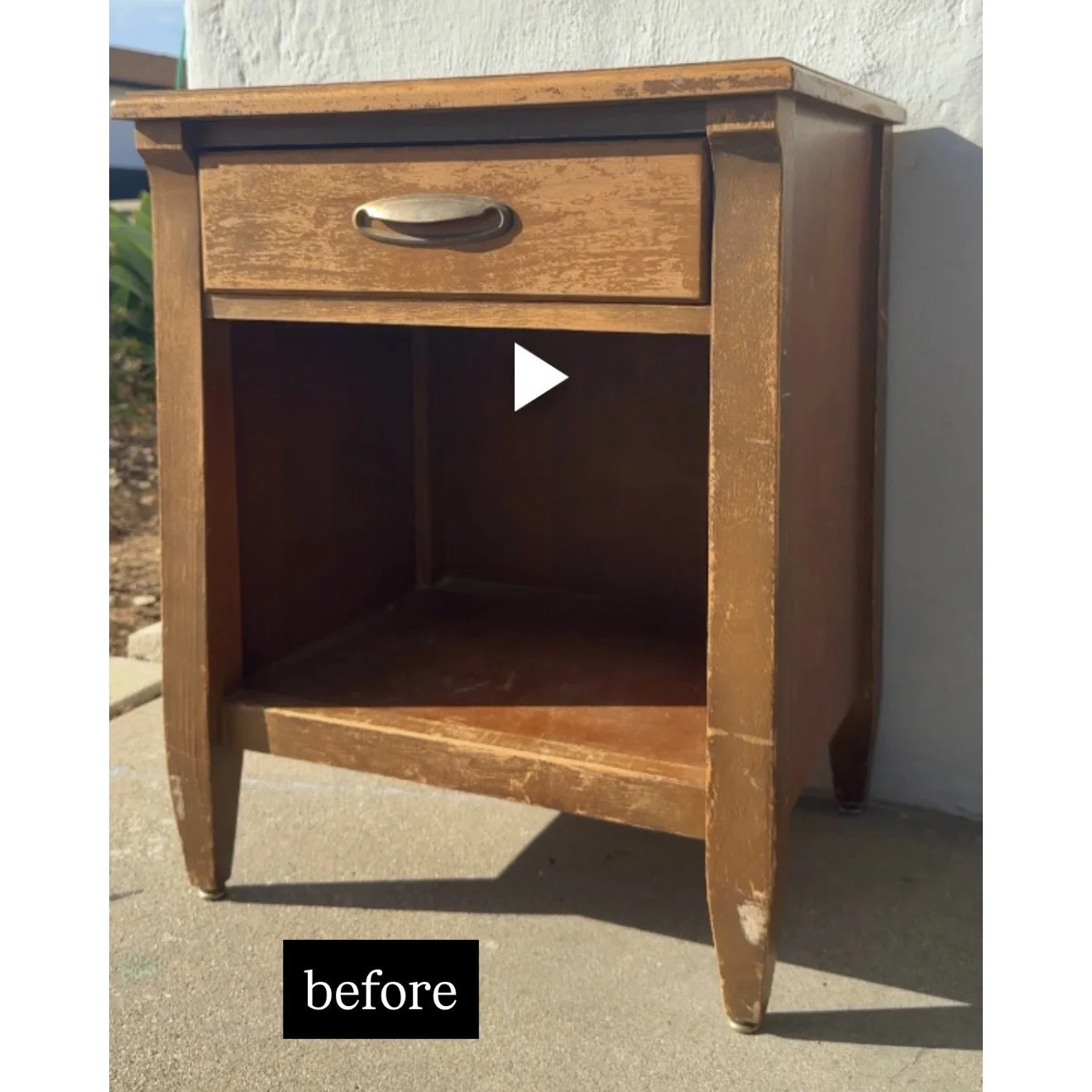 A wooden bedside table with a single drawer and an open storage compartment below, showing signs of wear and scratches.