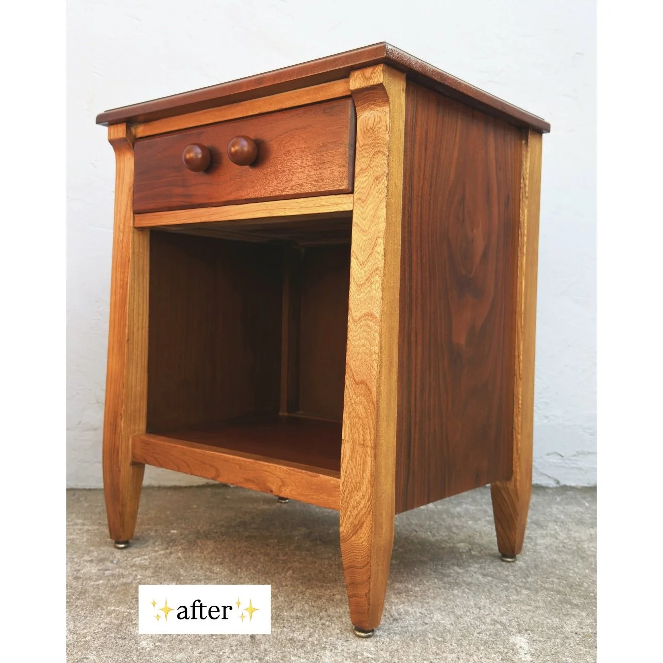 Refinished wooden nightstand with a single drawer and round knobs, positioned against a white wall on a concrete floor.