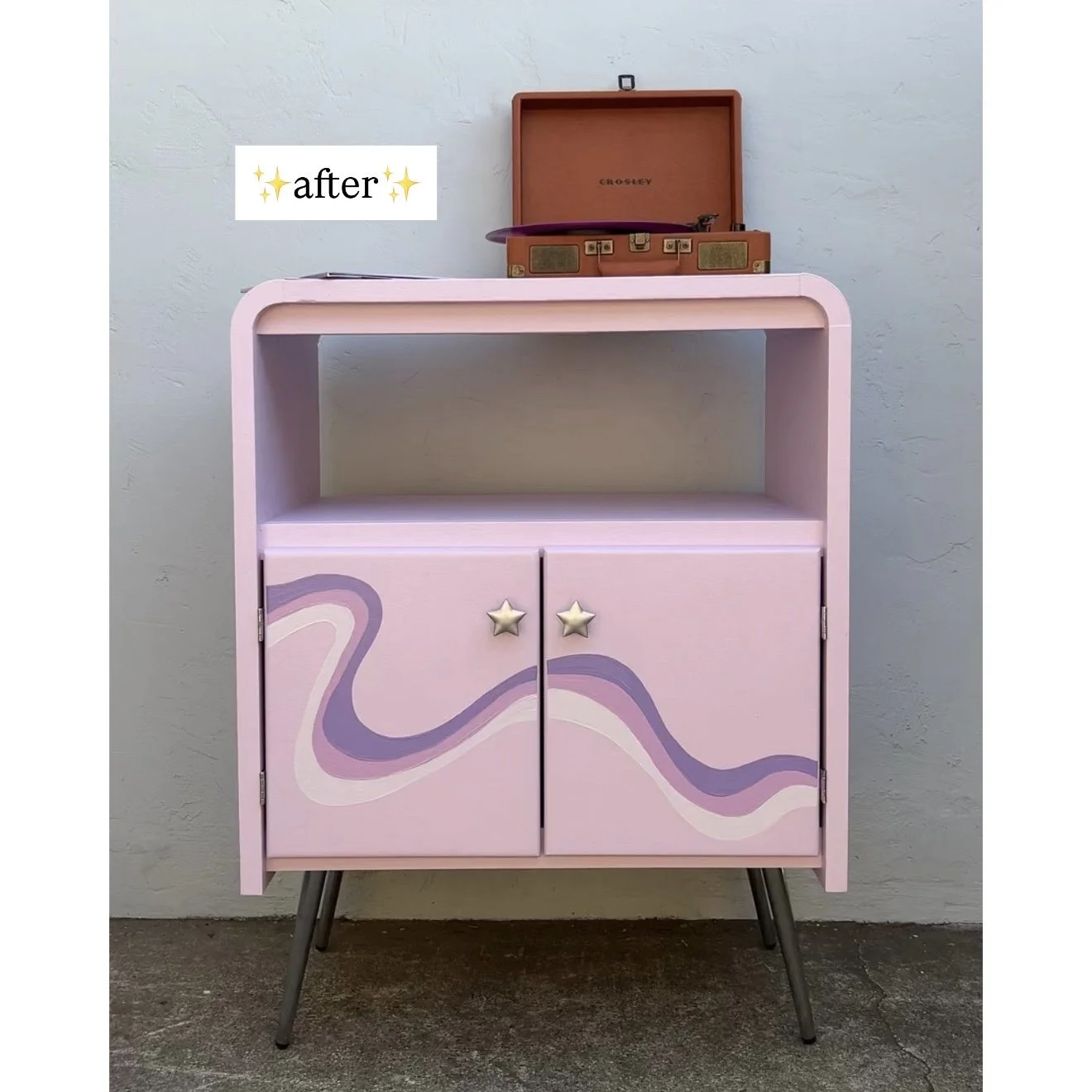 Pink vintage cabinet with purple swirl design on doors, star-shaped knobs, standing on angled metal legs, with a record player and vinyl on top, against a white wall, labeled 'after'.