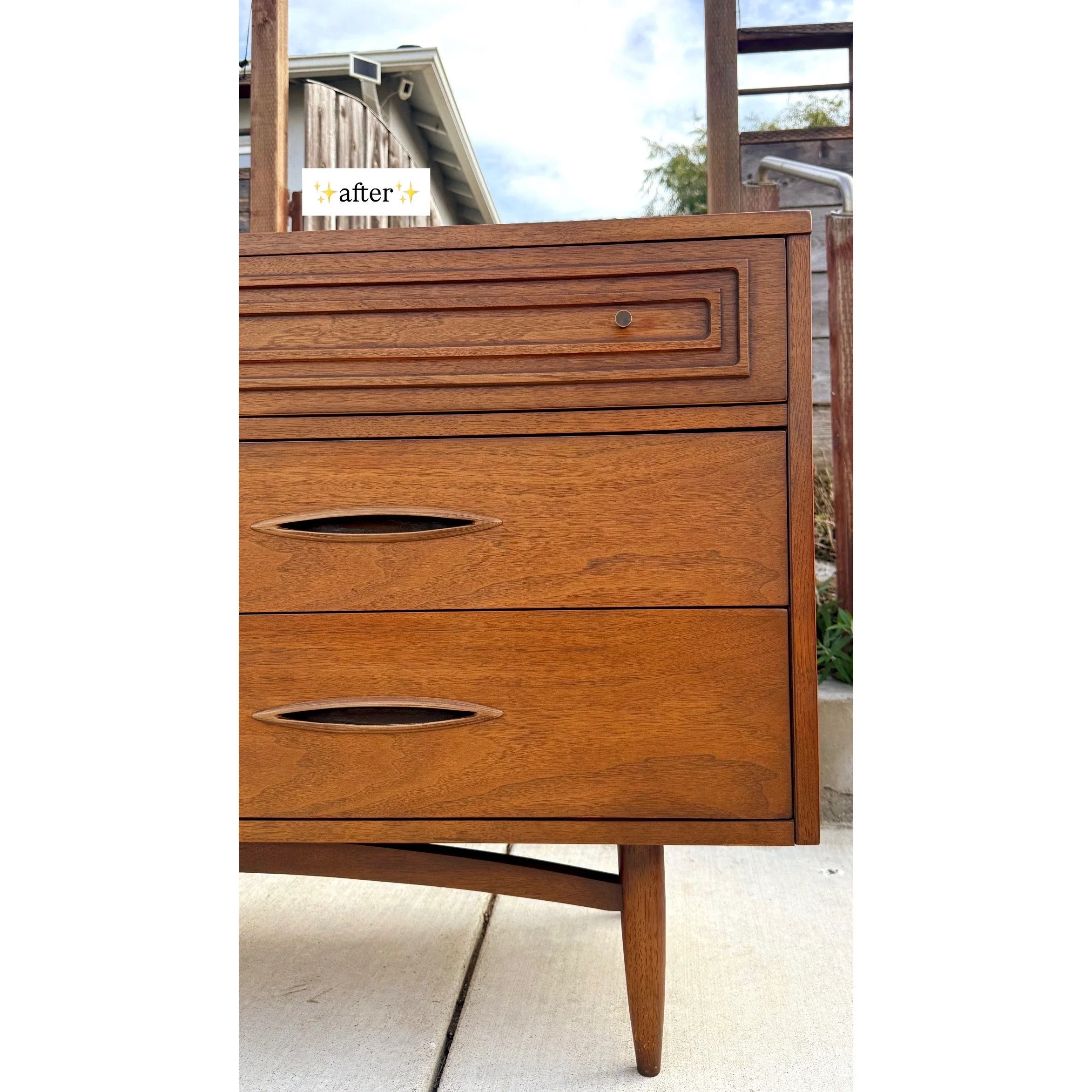 A vintage wooden dresser with three drawers, featuring oval-shaped handles, situated outdoors on a concrete surface with a house and garden in the background. The word 'after' with sparkles is overlaid in the top left corner.