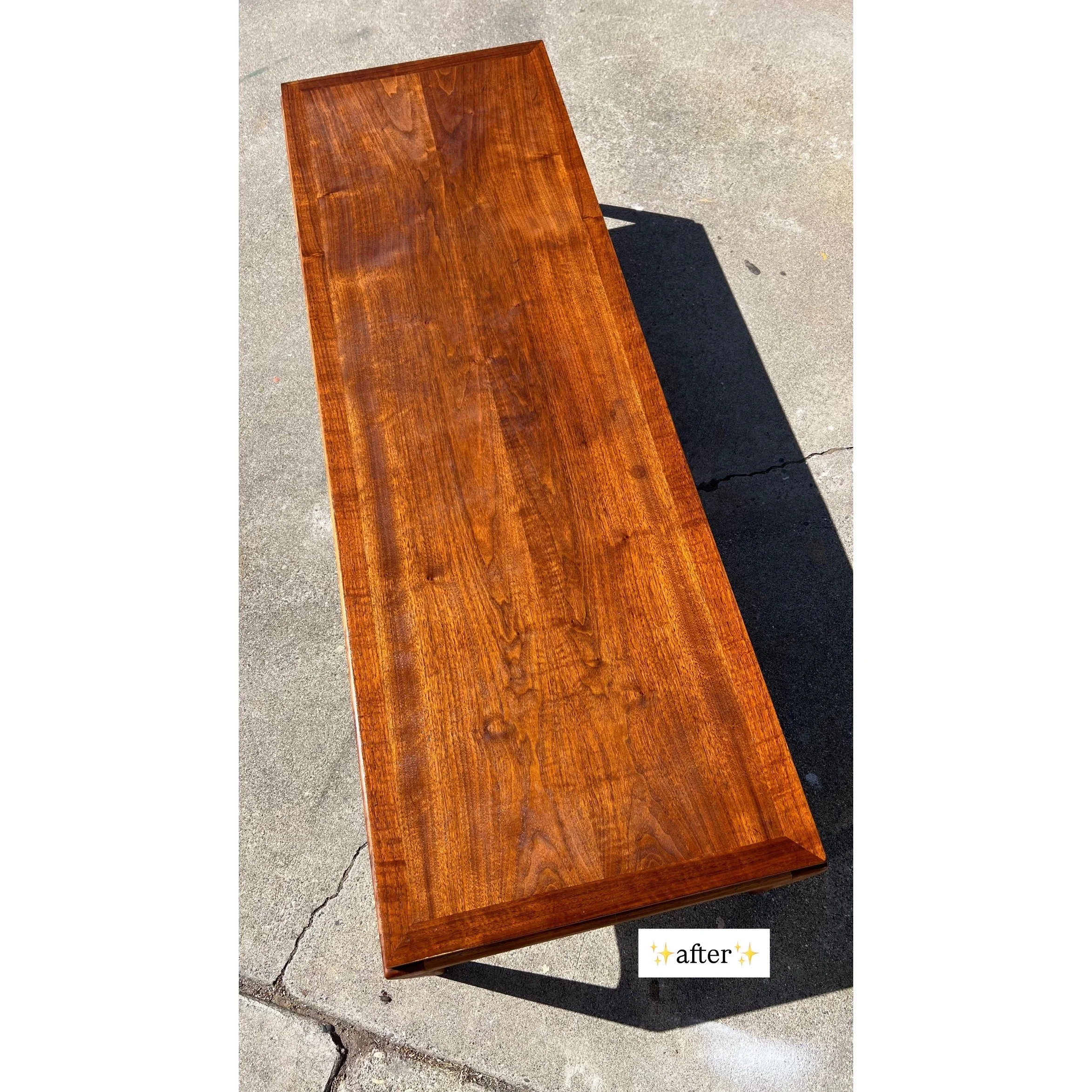 A polished wooden bench outdoors on concrete pavement with a long shadow cast beside it. Text overlay reads 'after' with sparkles.