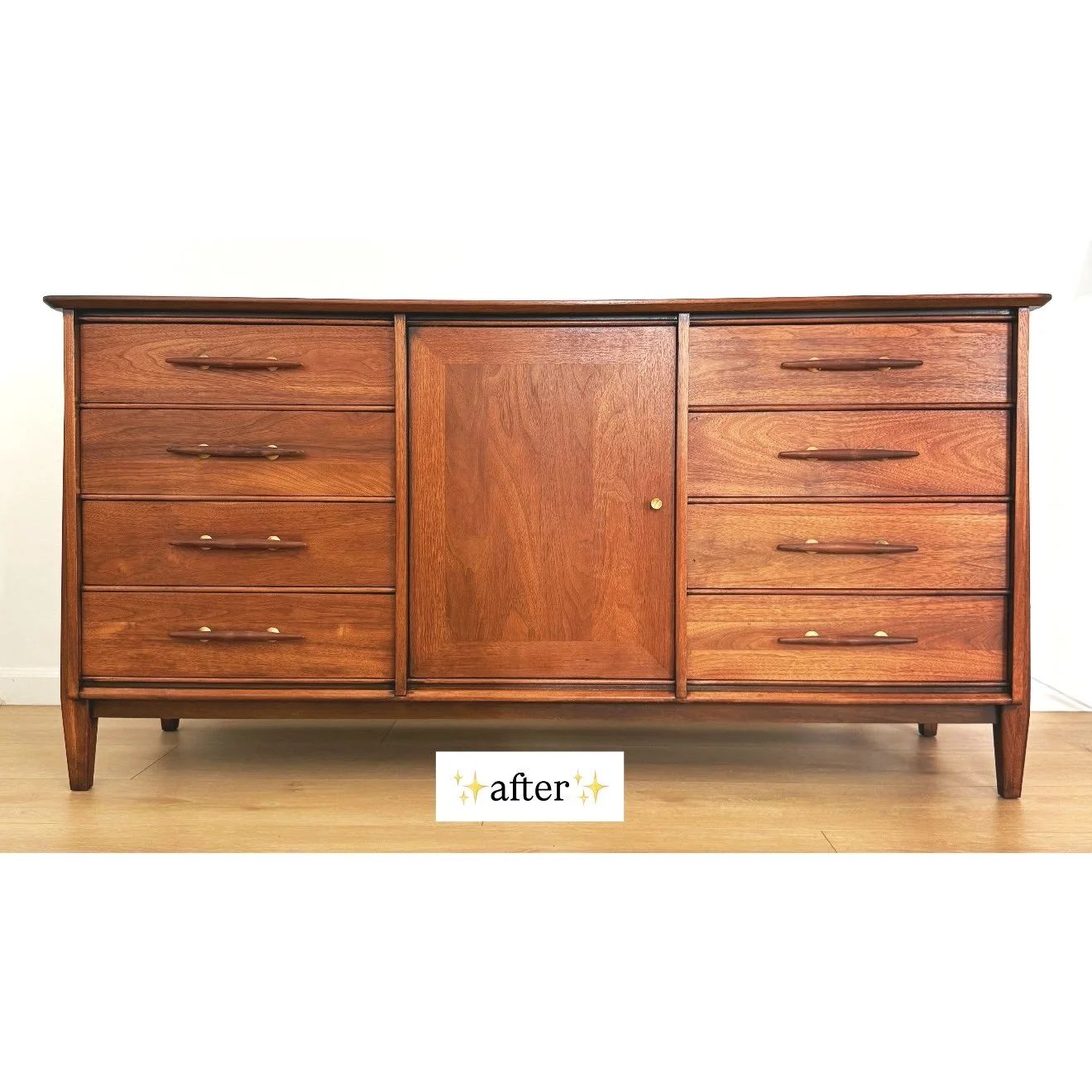 A wooden dresser with multiple drawers and a central cabinet, all polished to a shiny finish, placed against a white wall on a hardwood floor.