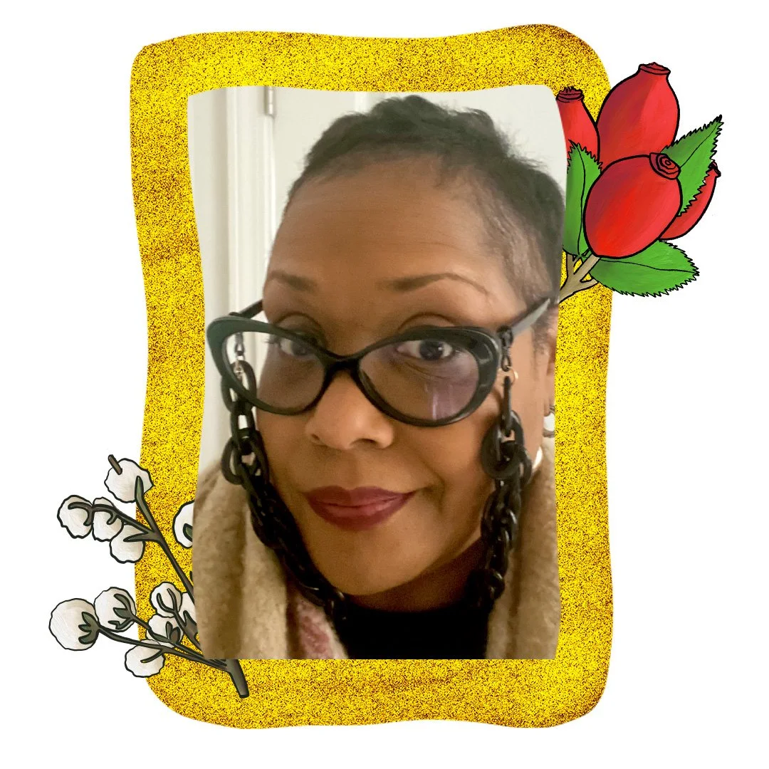 A headshot of Lisa Anderson - she wears glasses with a large decorative chain and deep purple lips