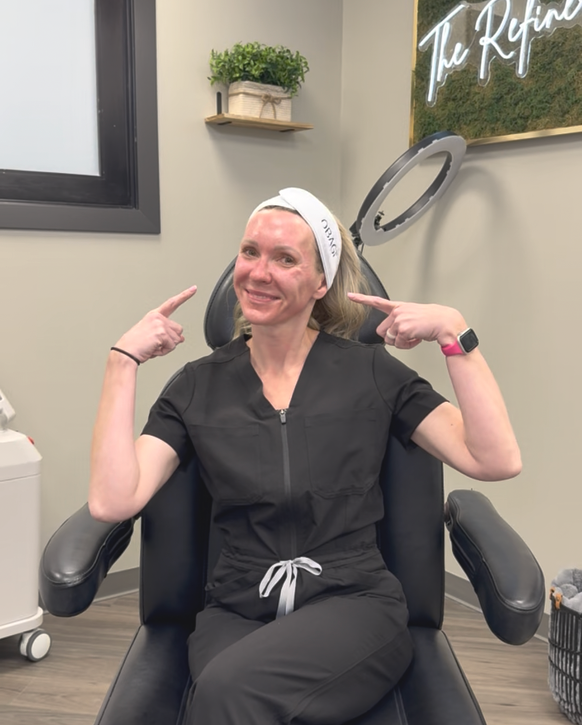 Close-up of a woman with light skin, green eyes, freckles, and red hair, holding her face with her right hand, against a neutral beige background.