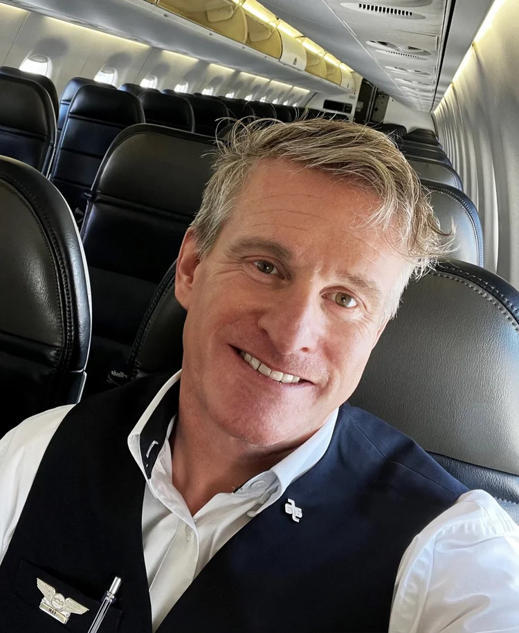 SkyWest Flight Attendant seated in the cabin, wearing an AFA pin