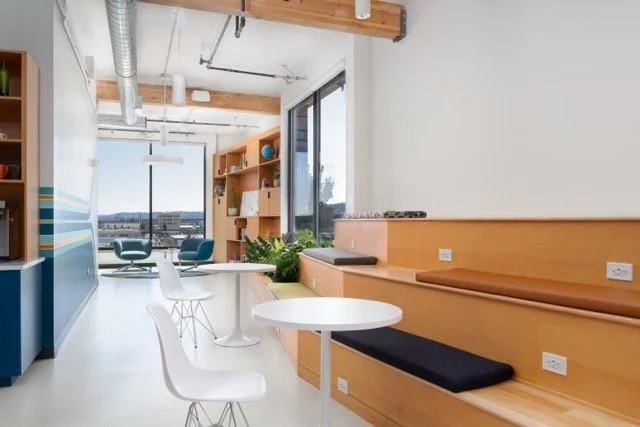 Modern creative office featuring stadium seating, floor-to-ceiling windows with views of the Portland, Oregon cityscape, and biophilic design elements