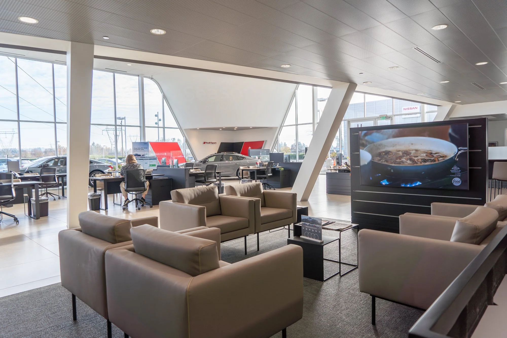Modern auto dealership design for Audi in Wilsonville, Oregon, featuring a customer waiting area with expansive windows, natural light, and sleek contemporary furnishings