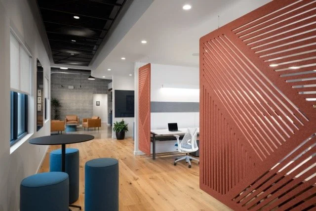 Modern office interior in Hillsboro, Oregon featuring large felt acoustic panels, modern architectural lighting, and a soft seating breakout area