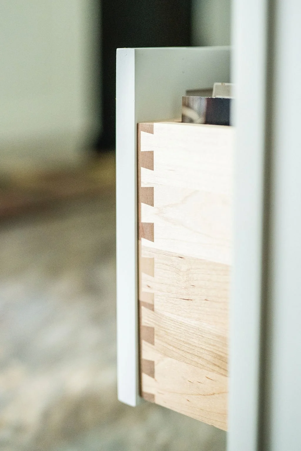 Close-up of a dovetail joint in a wooden drawer, showing precision craftsmanship with interlocking wood pieces.