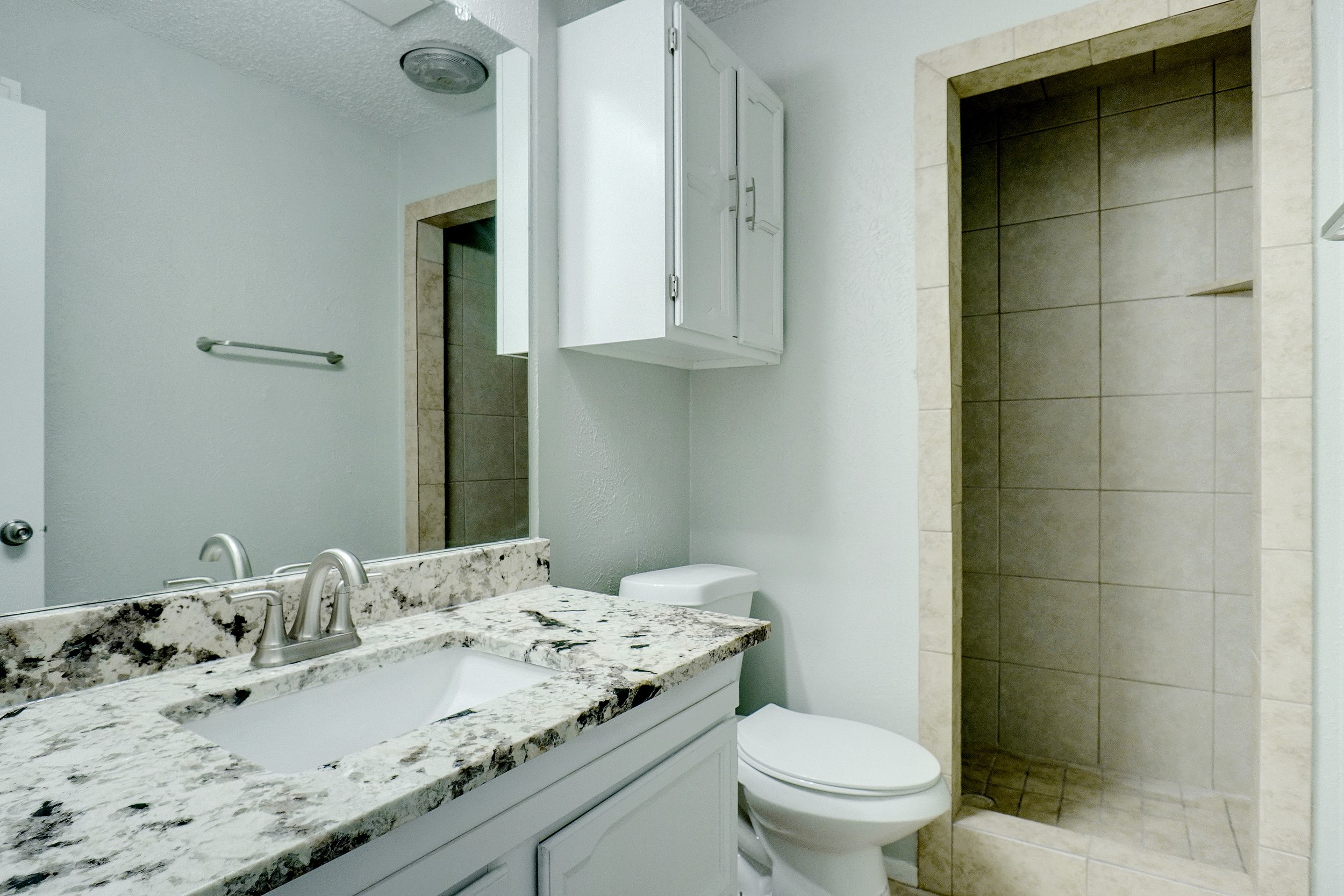 Guest bathroom with granite countertops and walk-in shower.