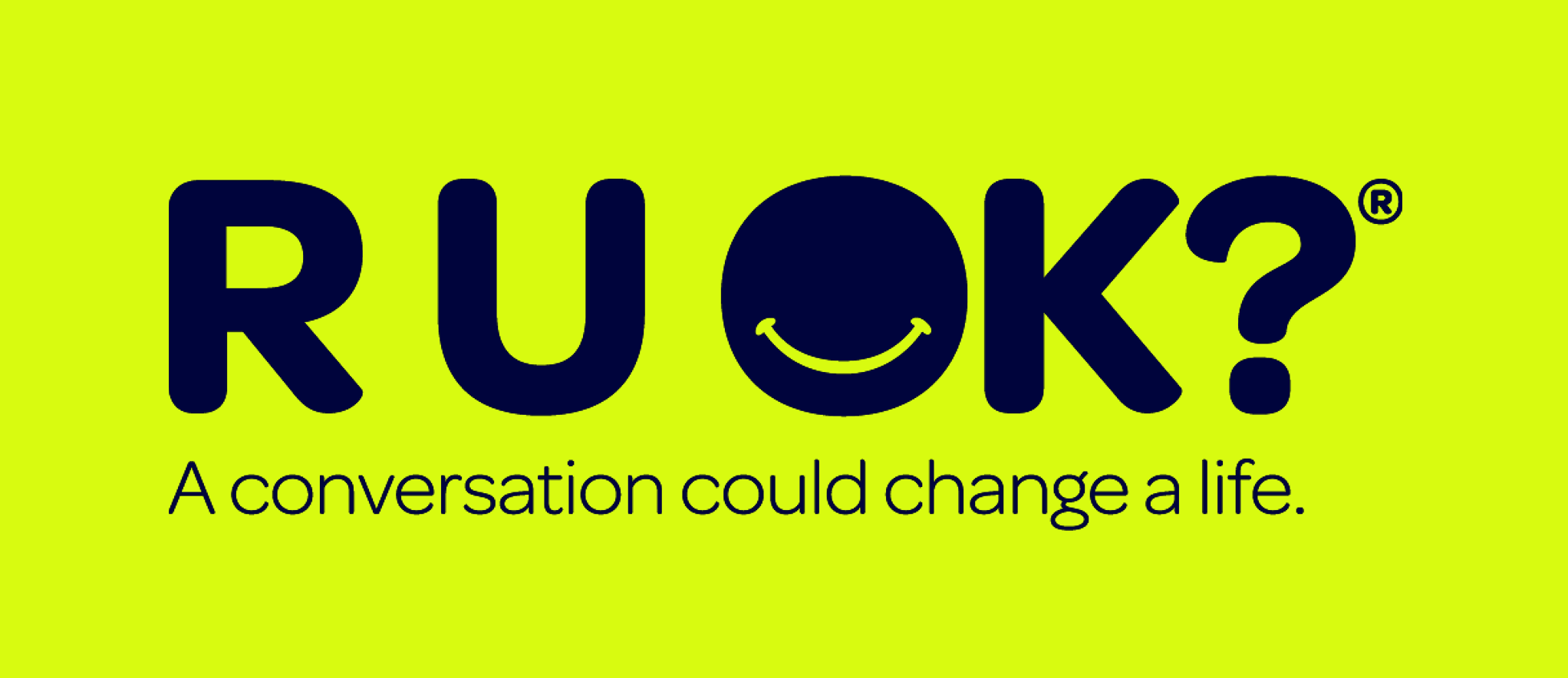 The word "RUOK?" in large dark blue letters on a light purple background, with a smiley face inside the letter "O." Below, there is a phrase that says "A conversation could change a life."