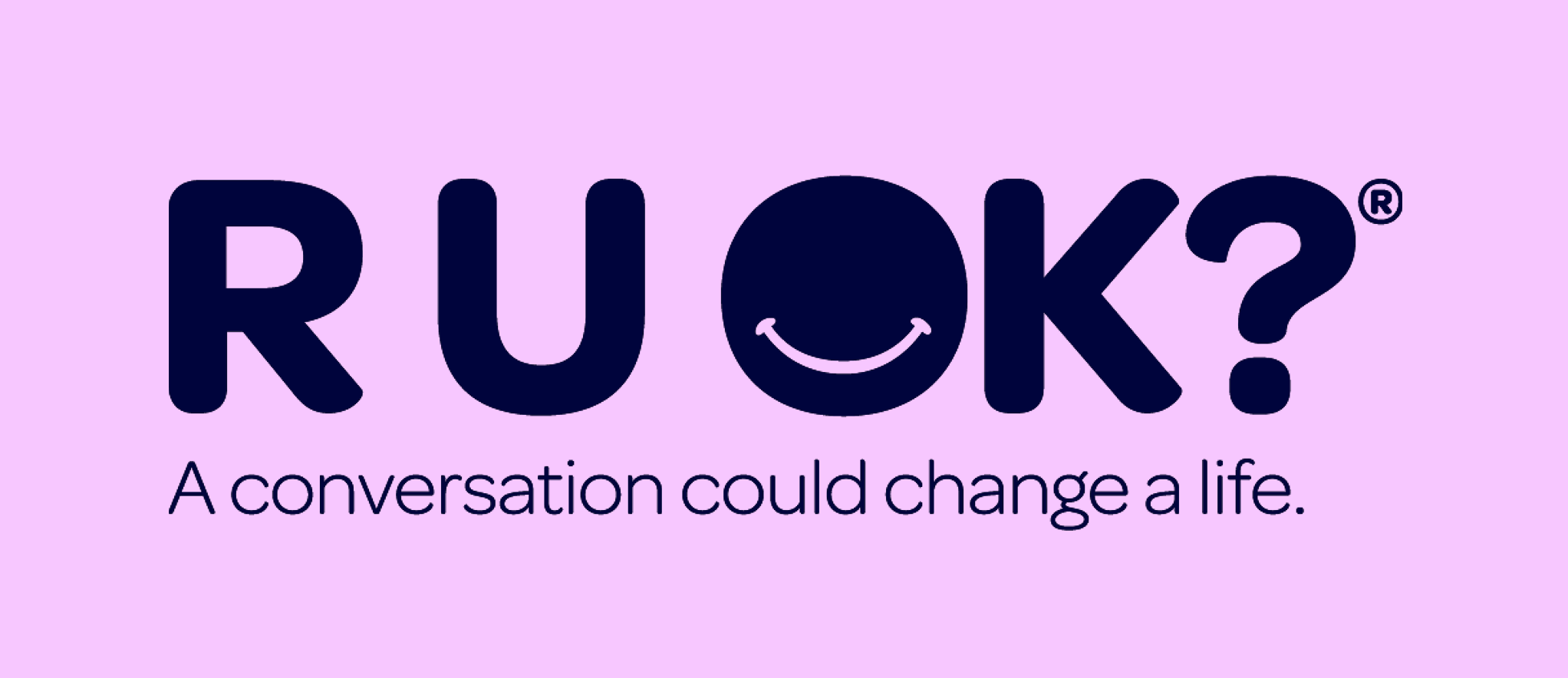 The word "RUOK?" in large dark blue letters on a light purple background, with a smiley face inside the letter "O." Below, there is a phrase that says "A conversation could change a life."