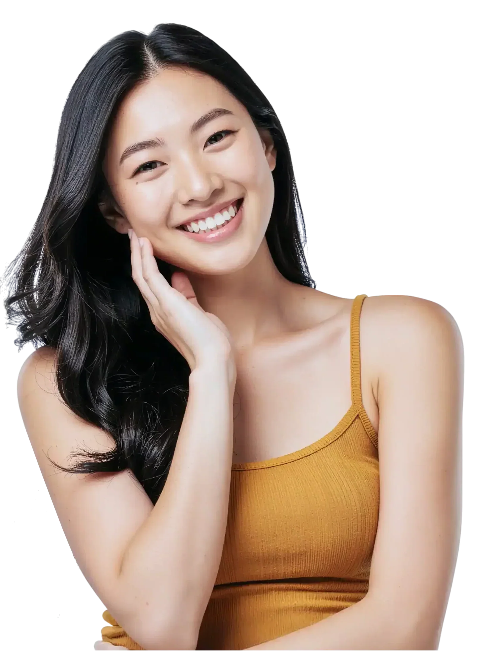 A young woman with long black hair smiling and touching her face, wearing a mustard yellow tank top.