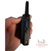 Close-up of a person's hand holding a black walkie-talkie device with an antenna and side buttons.