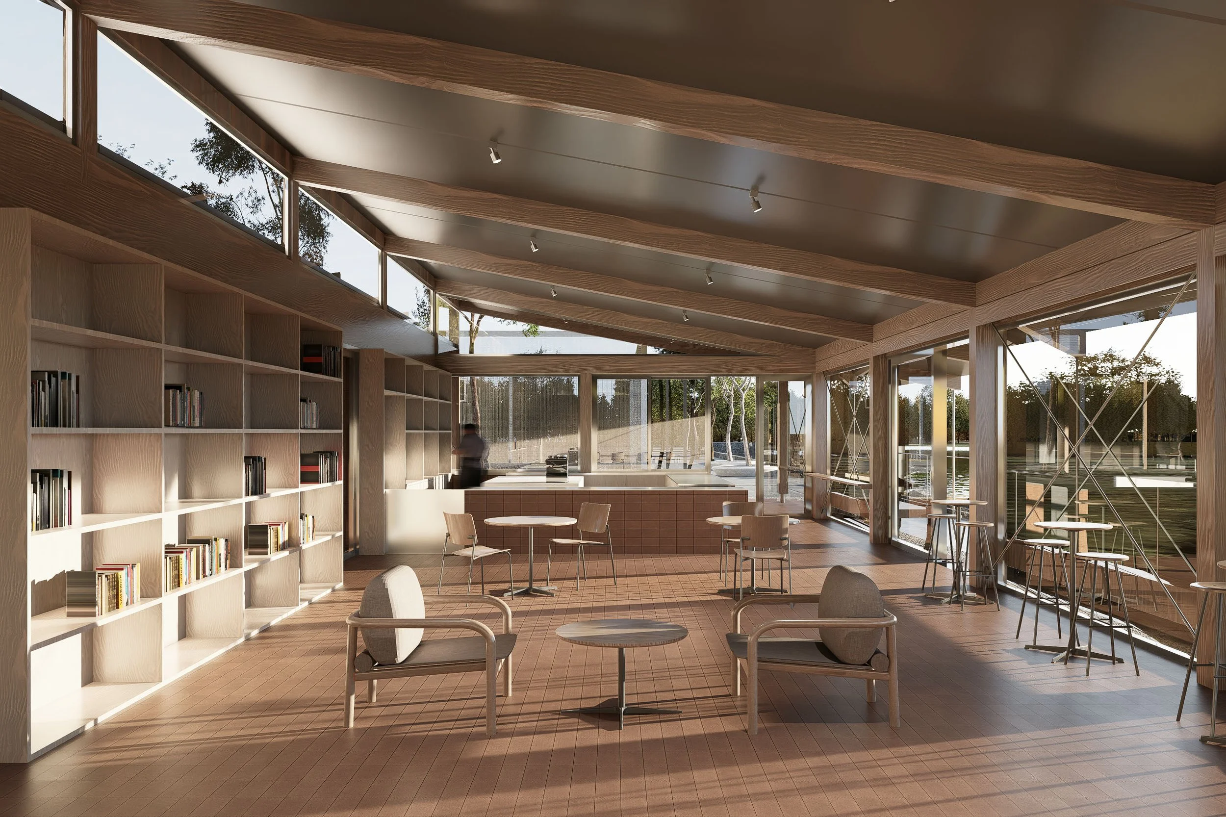 Modern indoor space with wooden flooring, large windows, bookshelves filled with books, seating areas with armchairs and small tables, bar stools near a window, and a person standing near a kitchen or counter area, with trees visible outside.