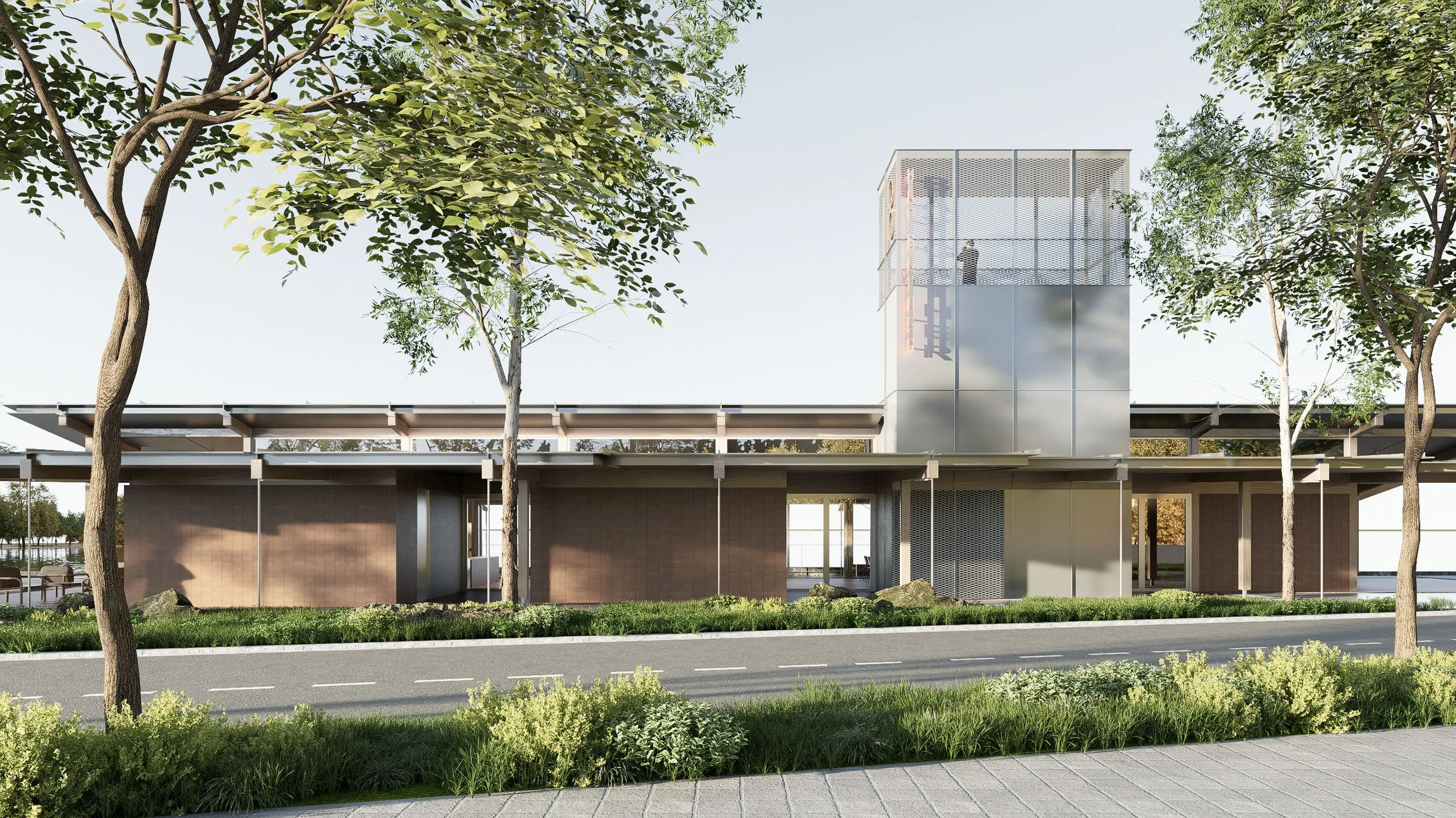 Modern multi-story building with glass and metal facade, surrounded by trees, with a road and sidewalk in the foreground.