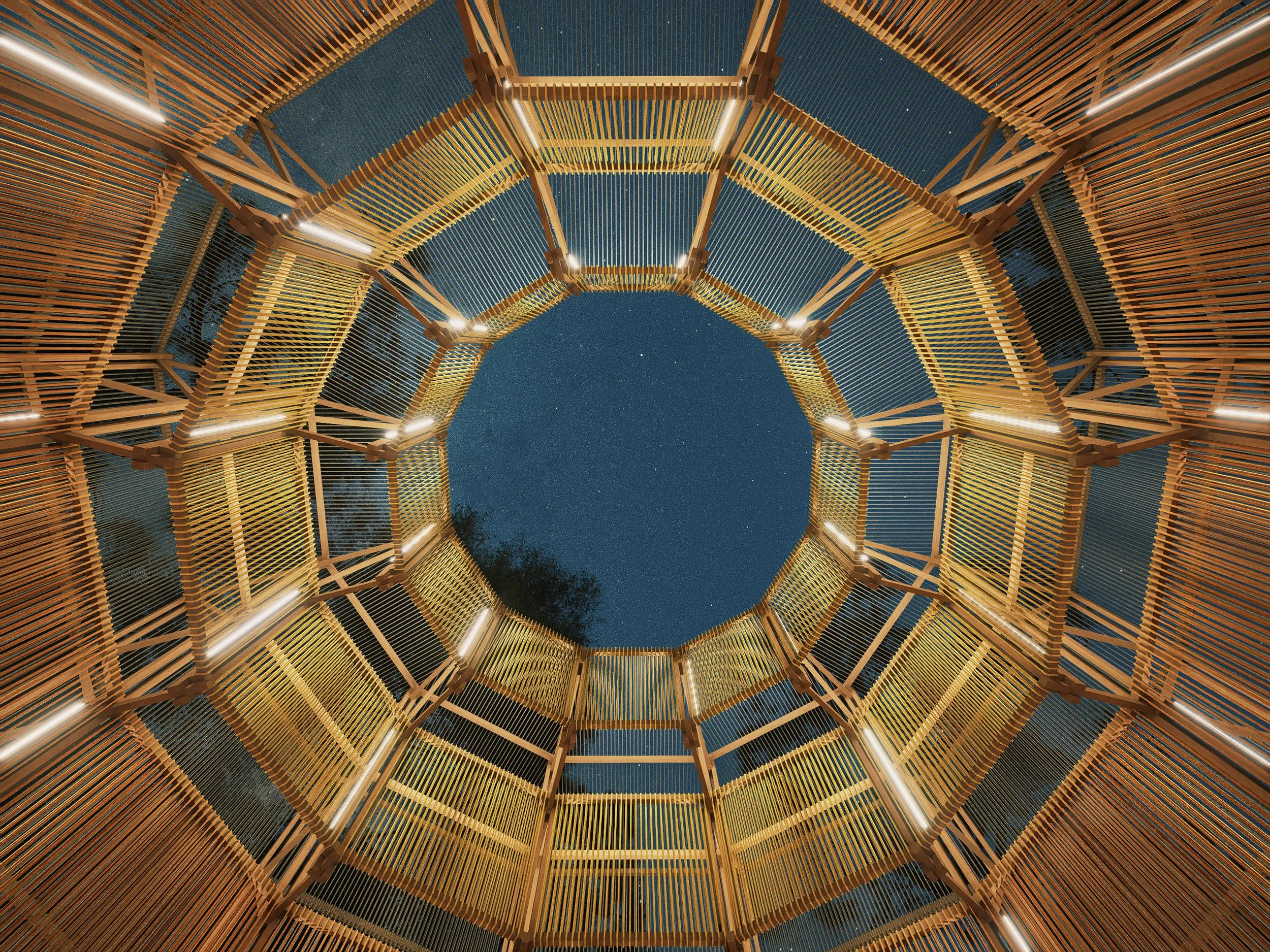 Looking up through the center of a multi-level wooden tower structure at night, showing a clear starry sky.
