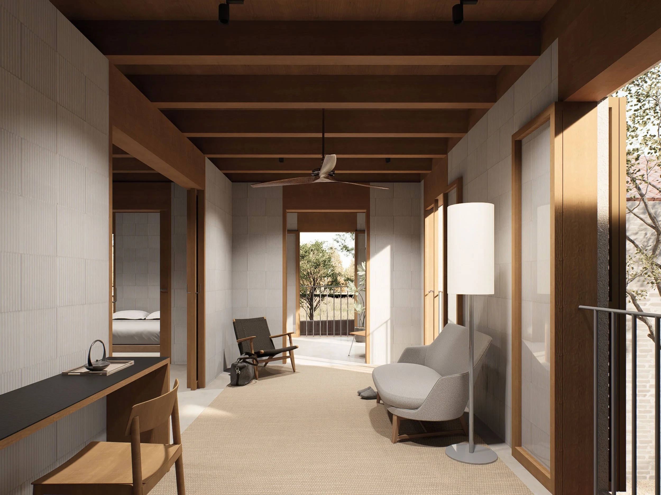 Living room with beige carpet, wooden ceiling beams, white walls, and large windows opening to a balcony with trees, furnished with a gray armchair, a floor lamp, a wooden chair, and a black wooden desk.