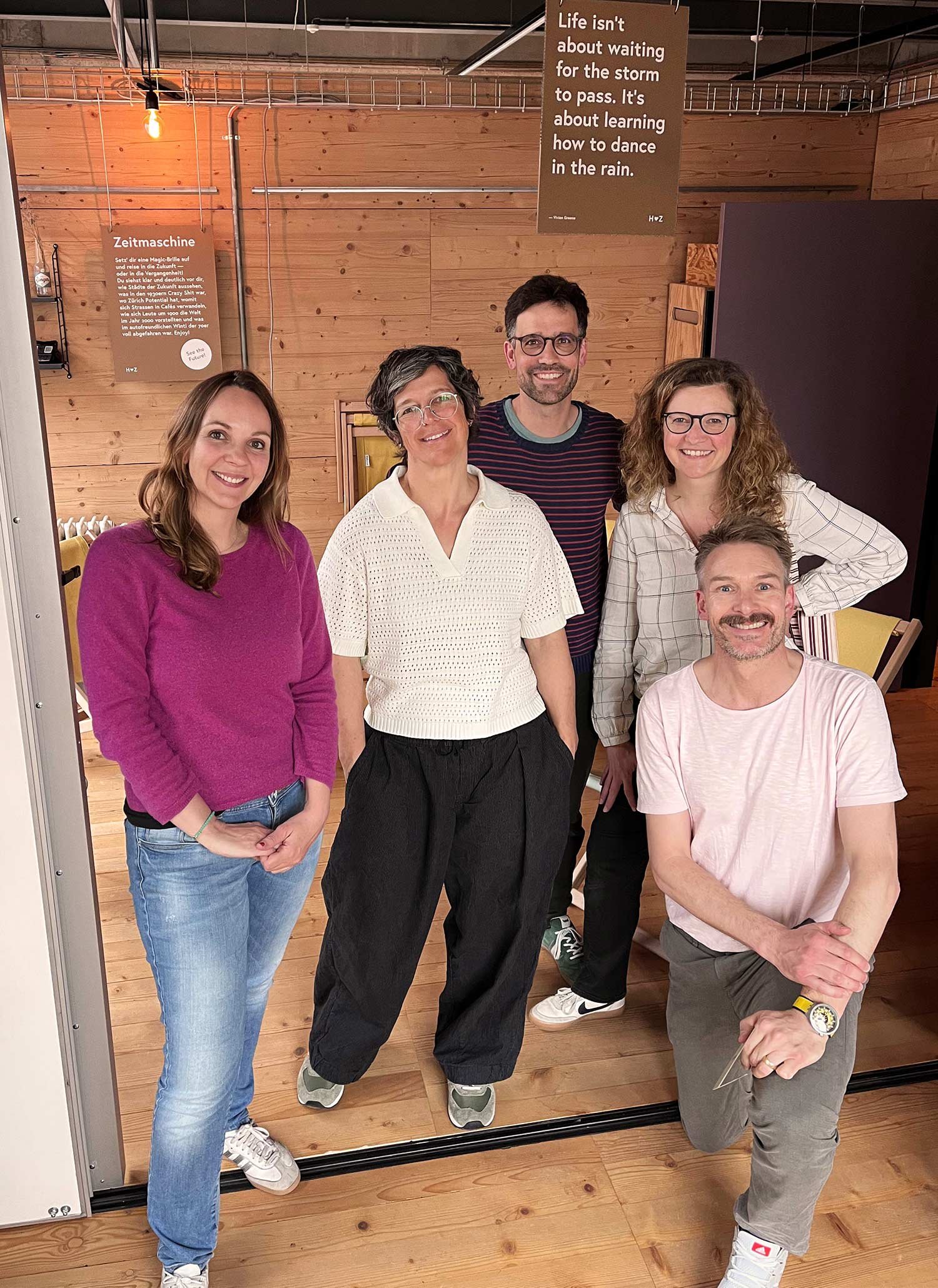 Fröhliches Teamfoto von Anja Hürlimann, Patricia Golling, Miro Ammann, Anja Egy und Sascha Völki im Roten Würfel mit Holzboden und Holzwänden.