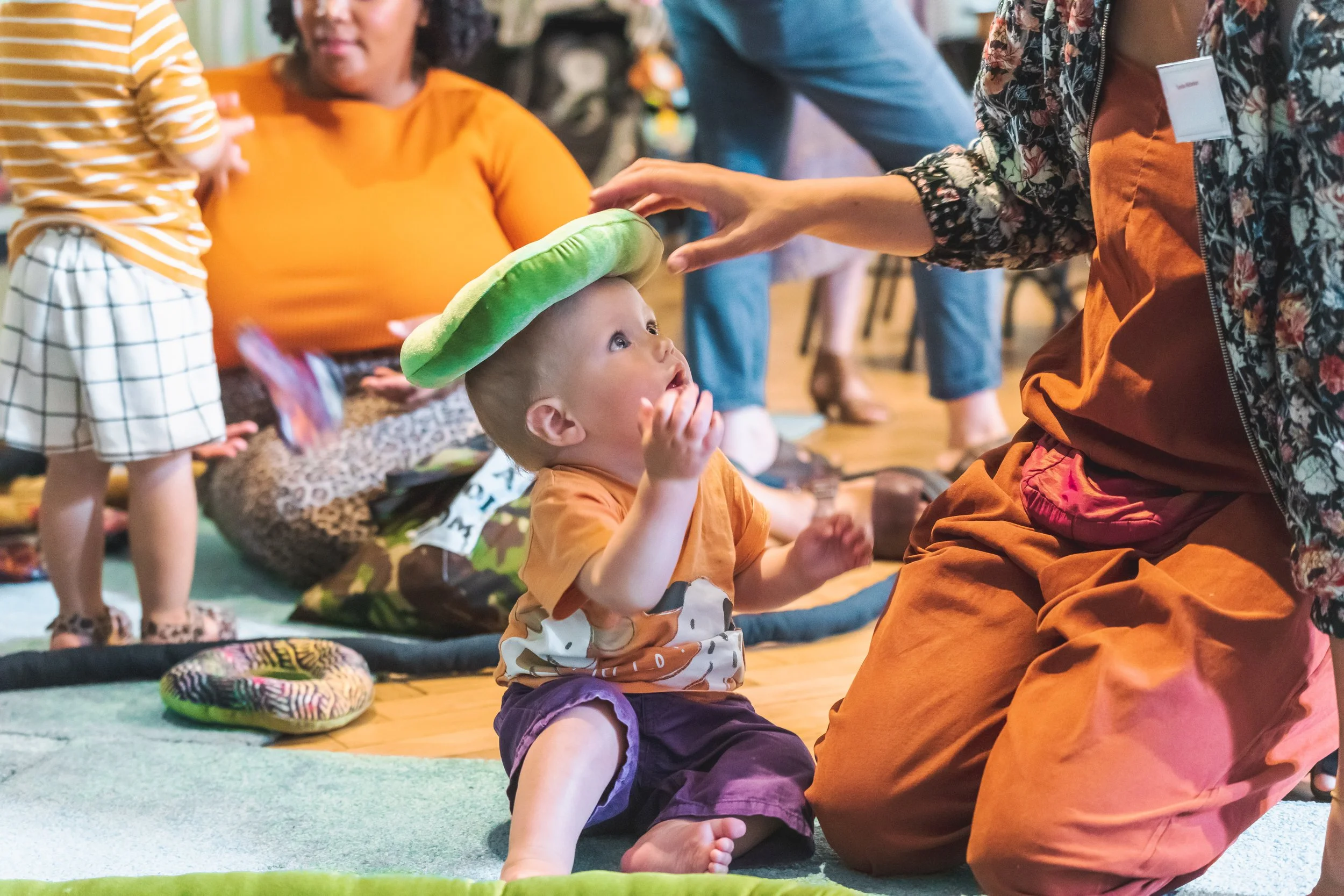 Photo of baby sitting up with fabric ring from soft play installation on his head.