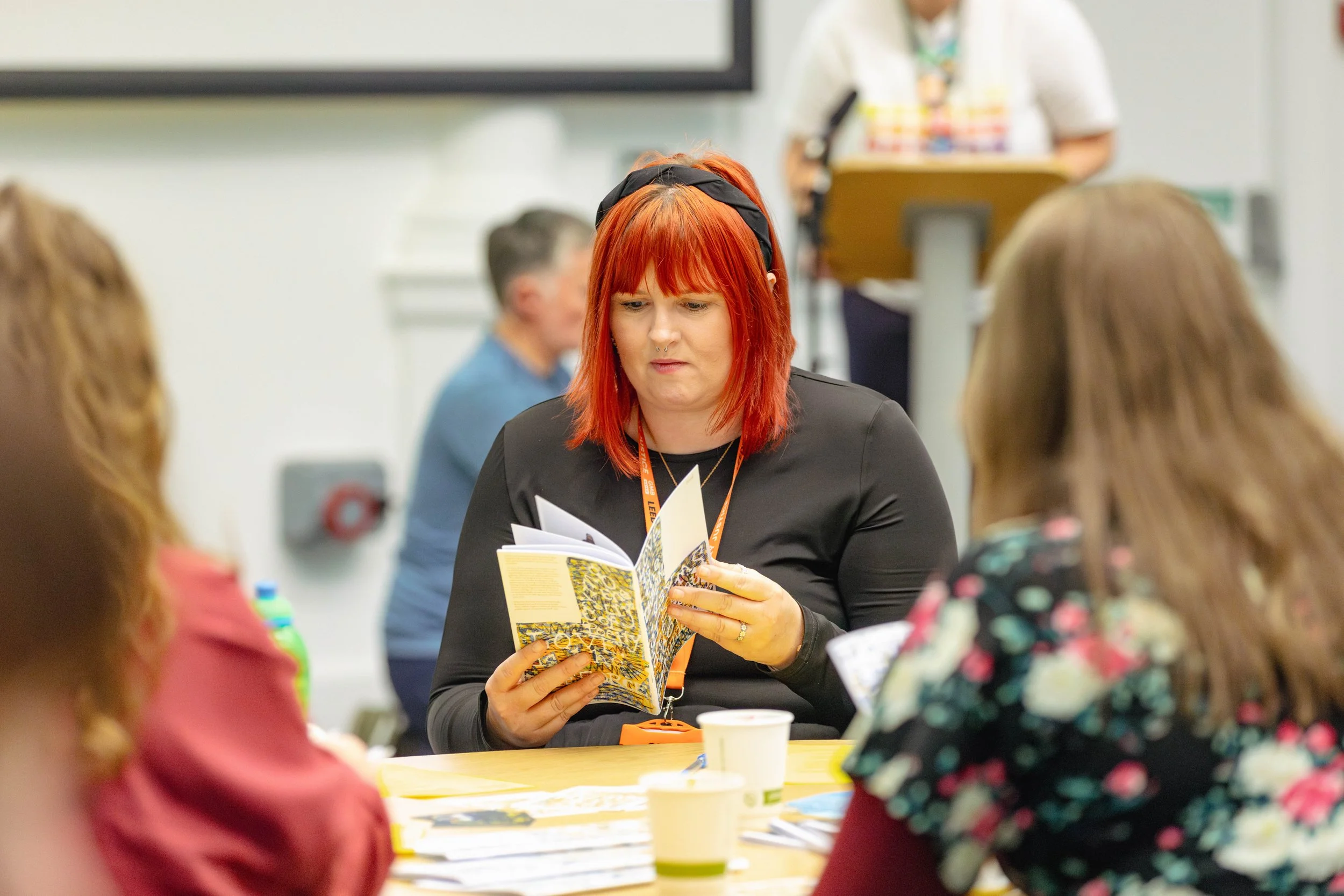 A woman with red hair reading a copy of the Feed Zine.