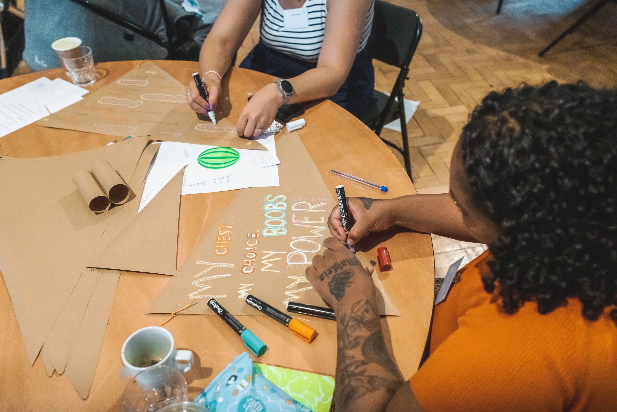 Photo of woman writing on flag, 'my chest, my choice, my boobs, my power'.