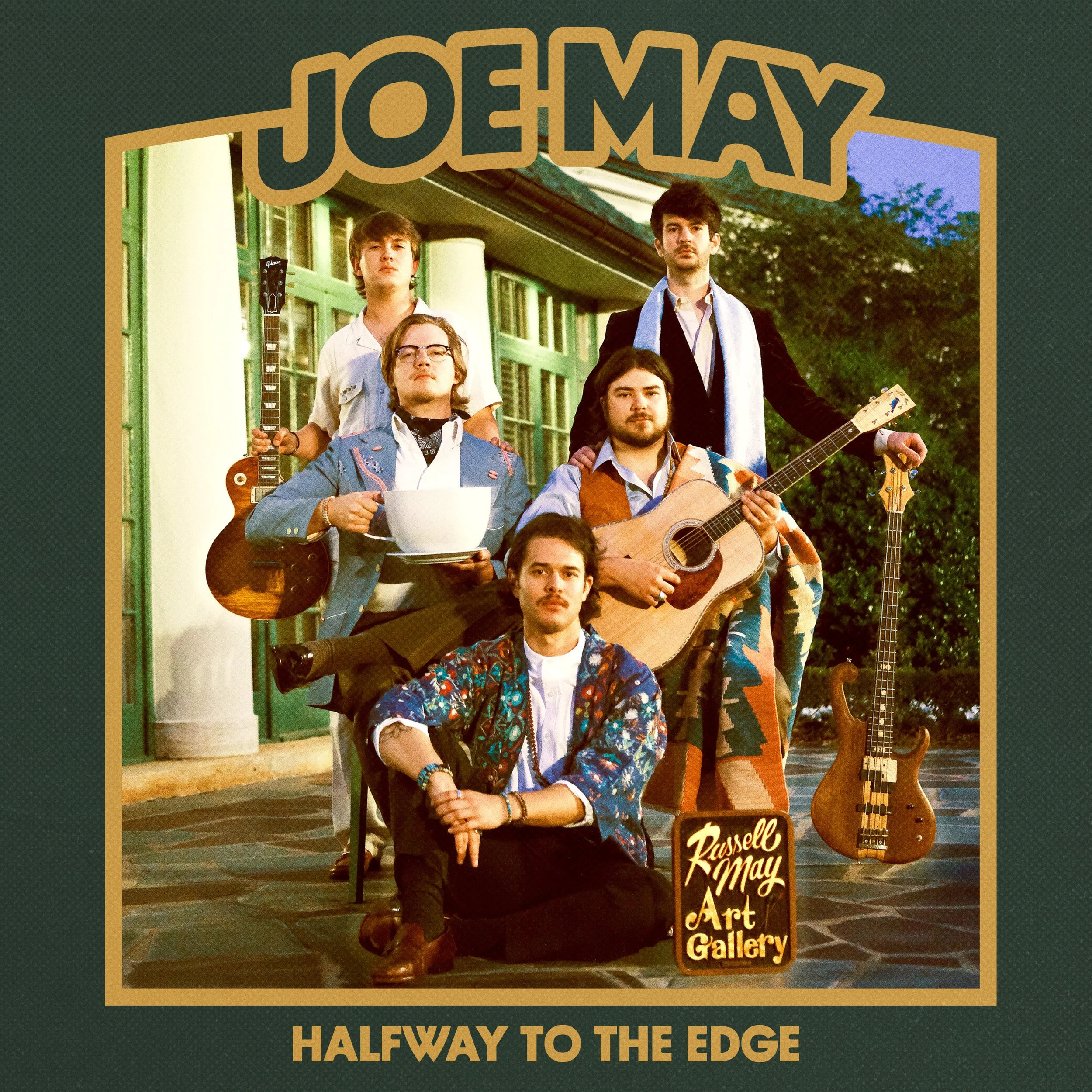 Group of five men in vintage attire, holding musical instruments, including a guitar and bass, in front of a building. Text reads 'Joe May' and 'Halfway to the Edge' with a sign indicating 'Russell May Art Gallery.'