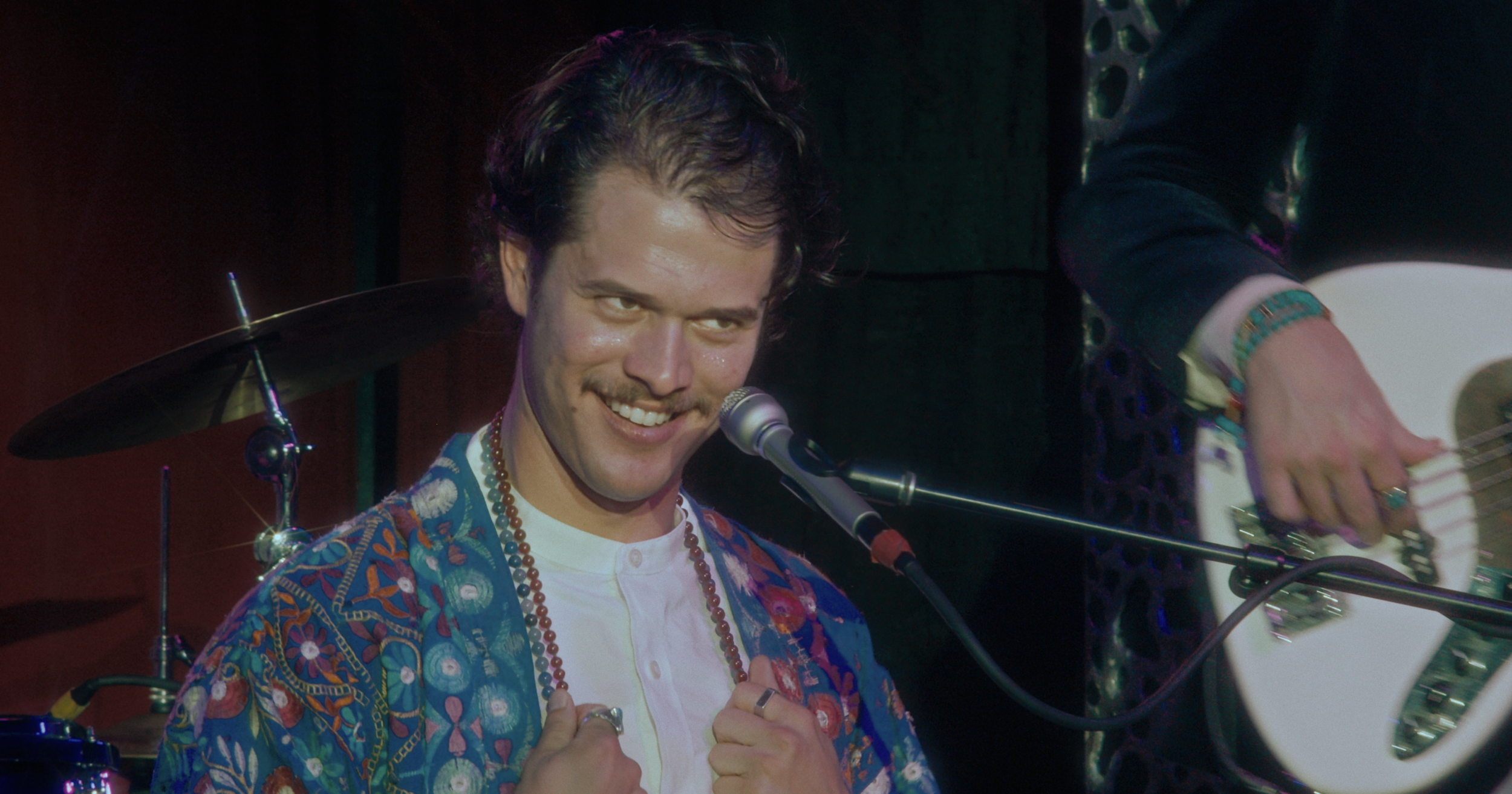 Joe May in colorful jacket playing keyboard on stage