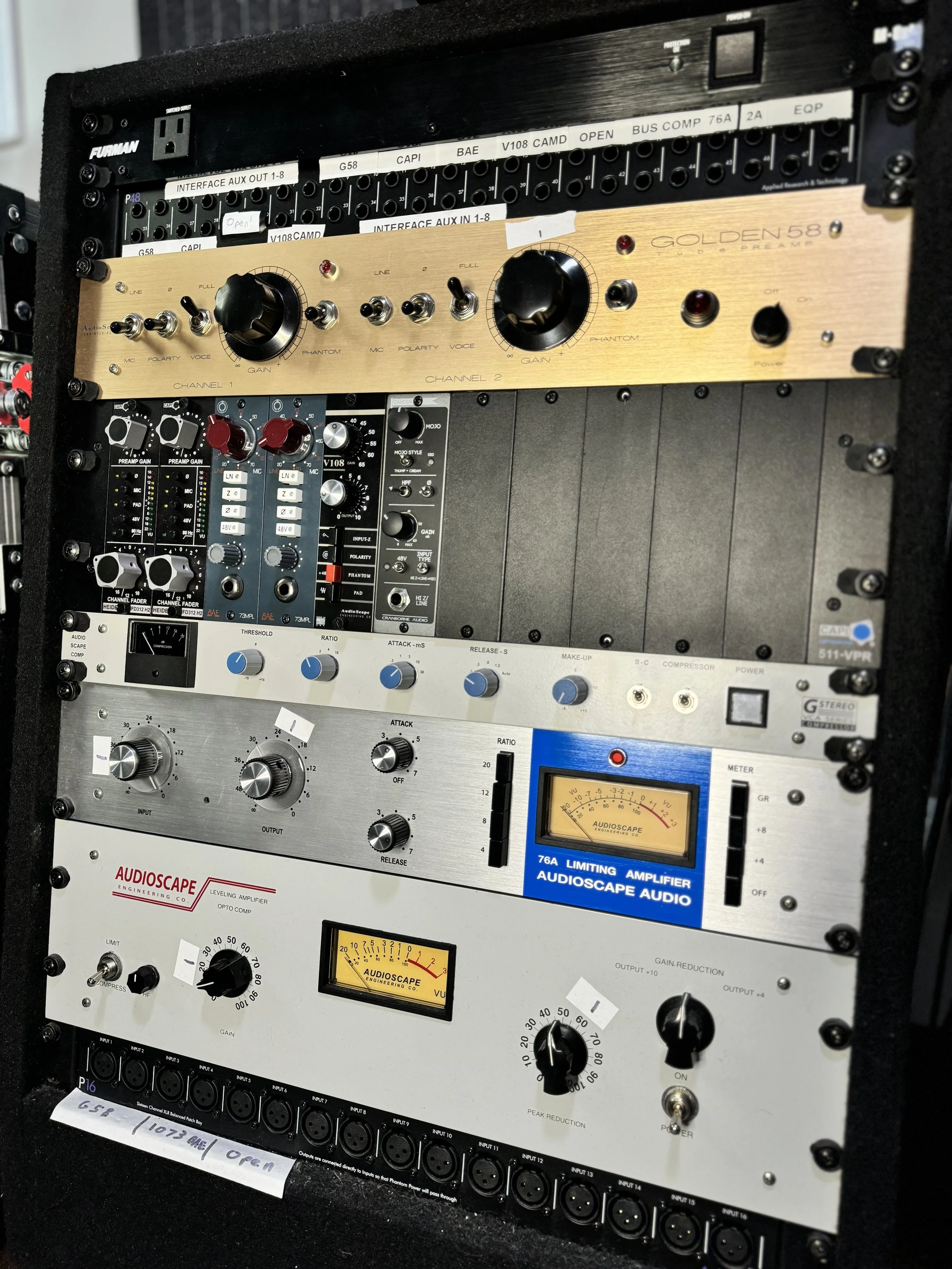 Rack-mounted audio equipment including preamps, limiters, and amplifiers with dials and meters.