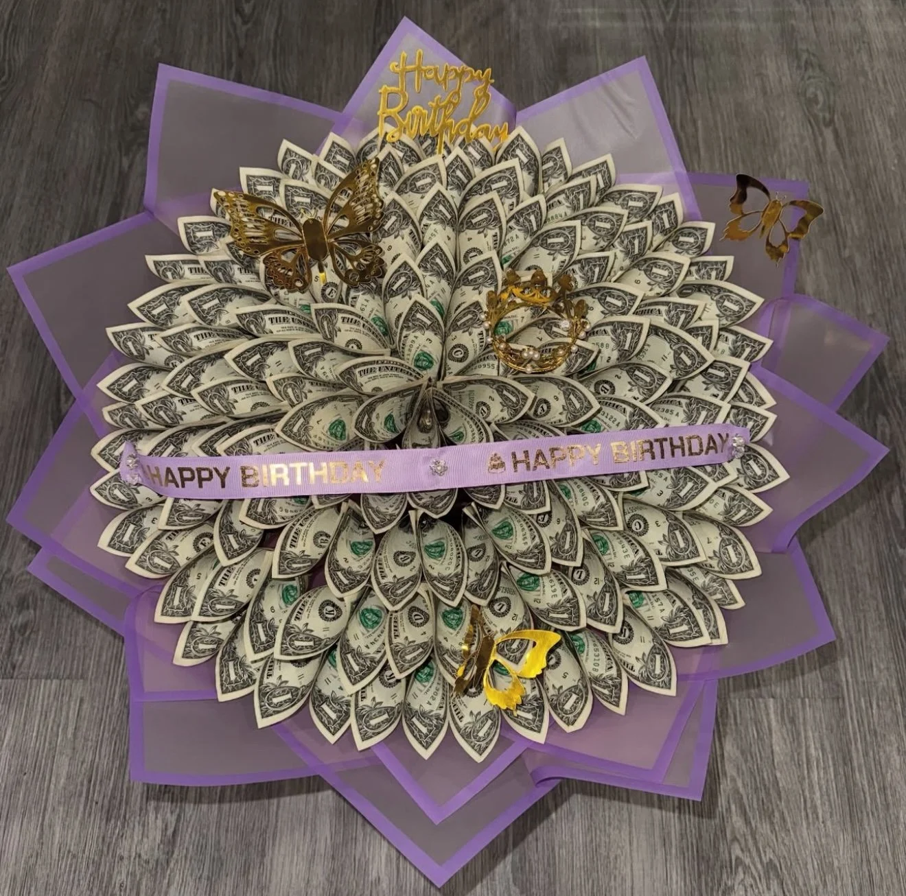 Money qbuquet made of folded one-dollar bills with gold butterfly decorations, a purple