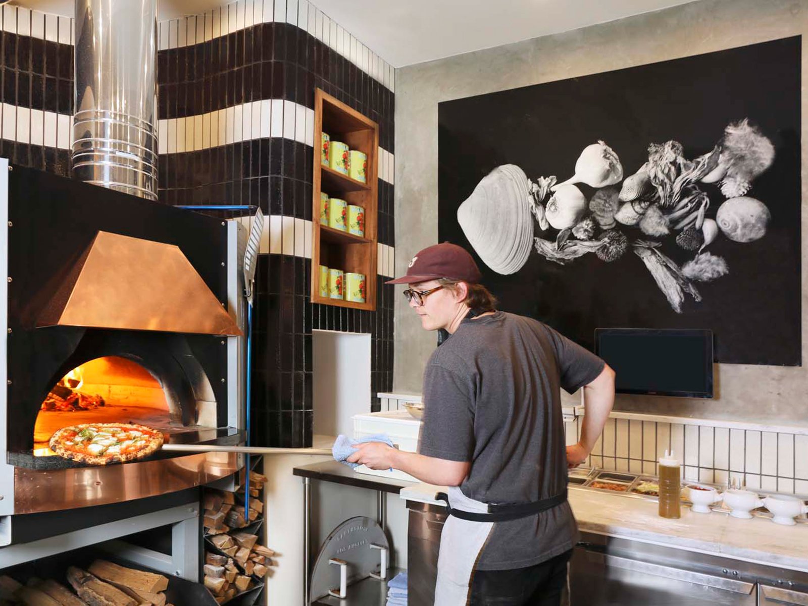 Team member removing pizza from wood-fired oven