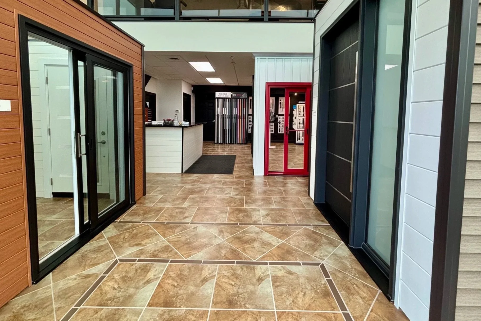Interior showroom displaying various styles of sliding glass doors, vinyl siding, and brick samples.