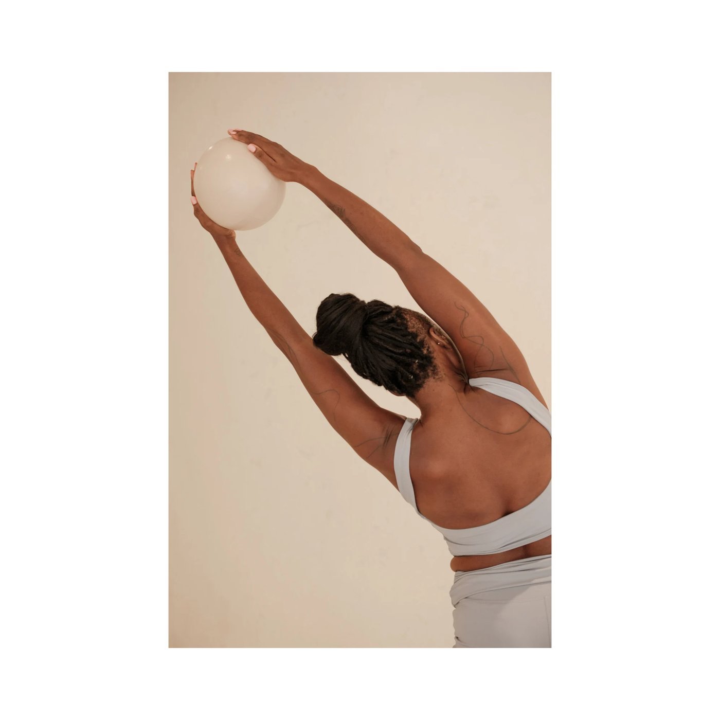 A woman stretching with an exercise ball overhead