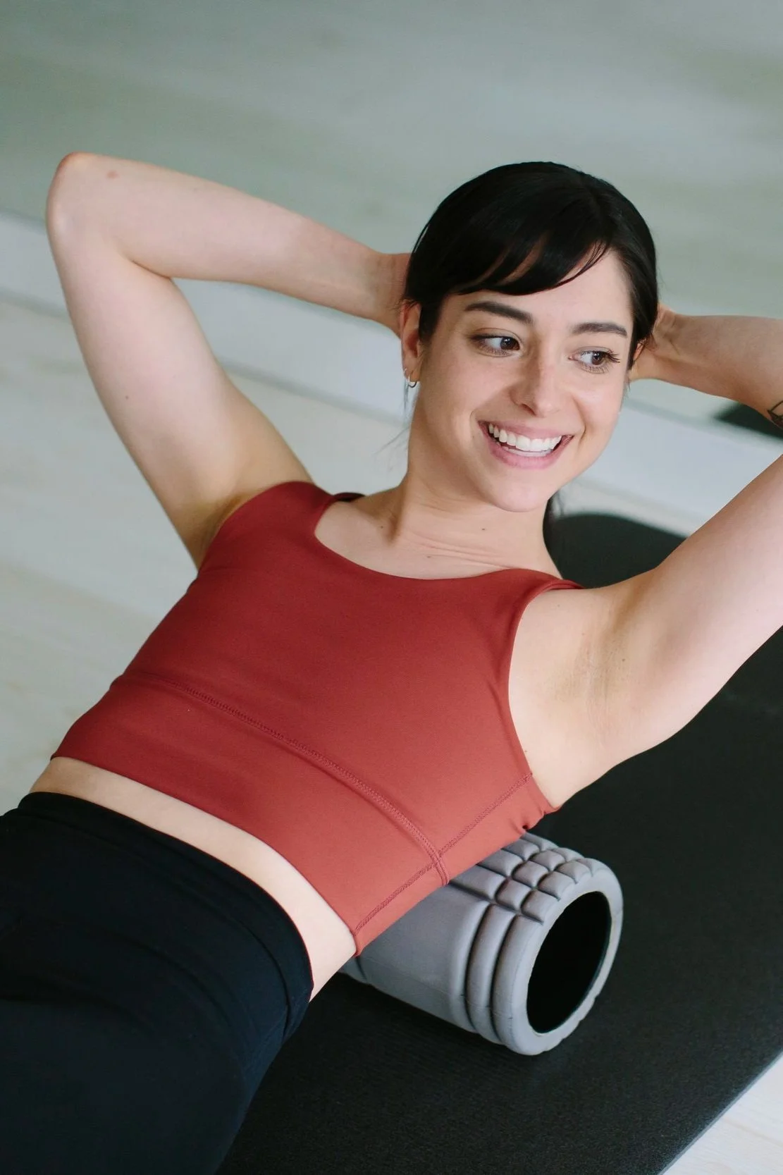 Maria Gardner, Director of Studio Operations smiles while doing Pilates mat exercise