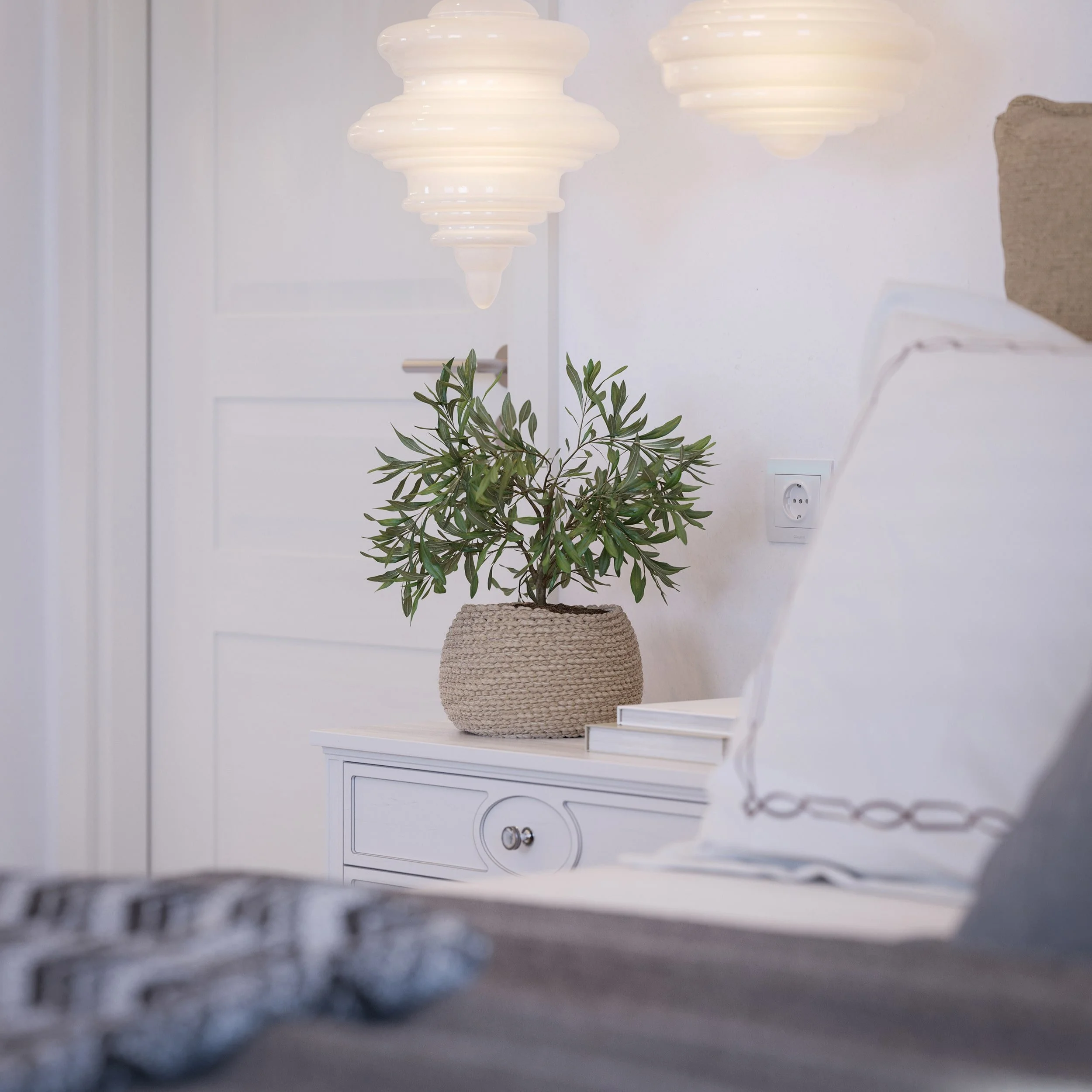 Interior architectural rendering of a minimalist bedroom corner in Mykonos with white nightstand, sculptural pendant lights, neutral bedding, natural textures and soft contemporary Cycladic styling.