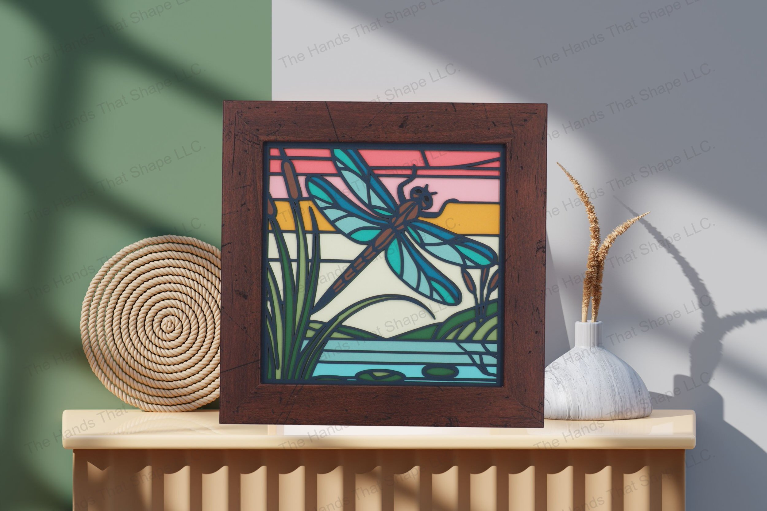 Behold this striking dragonfly-themed cardstock artwork, artistically displayed on a table, showcasing its vibrant layers and serene sunrise backdrop.