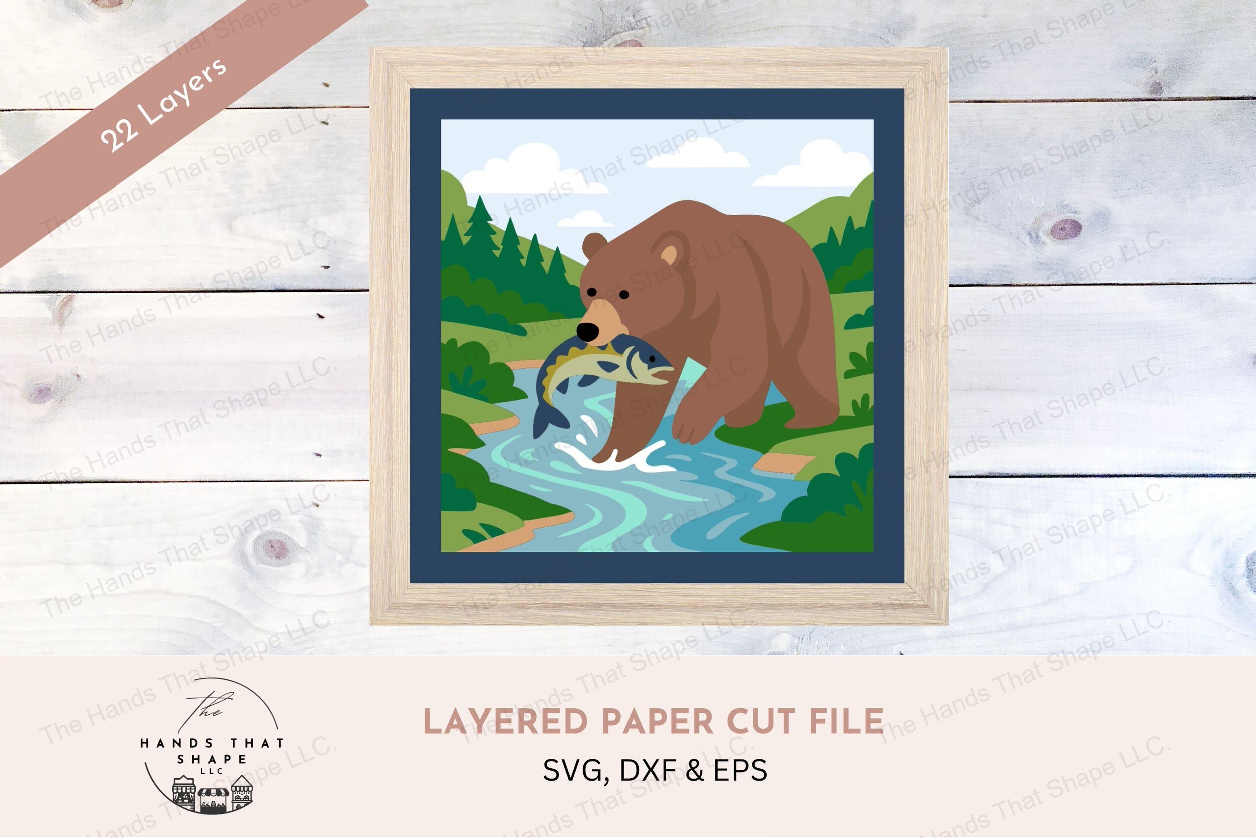 This layered cardstock art piece features a powerful grizzly bear standing in a stream with a fish in its mouth, set against a lush forest backdrop.
