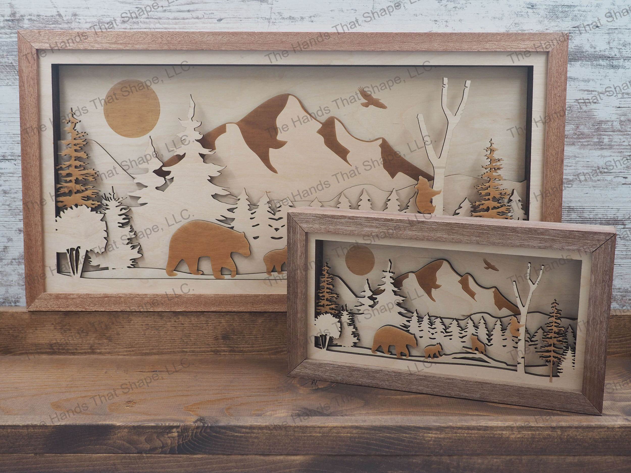mama bear and cubs traveling through a forest with a majestic mountain range towering above
