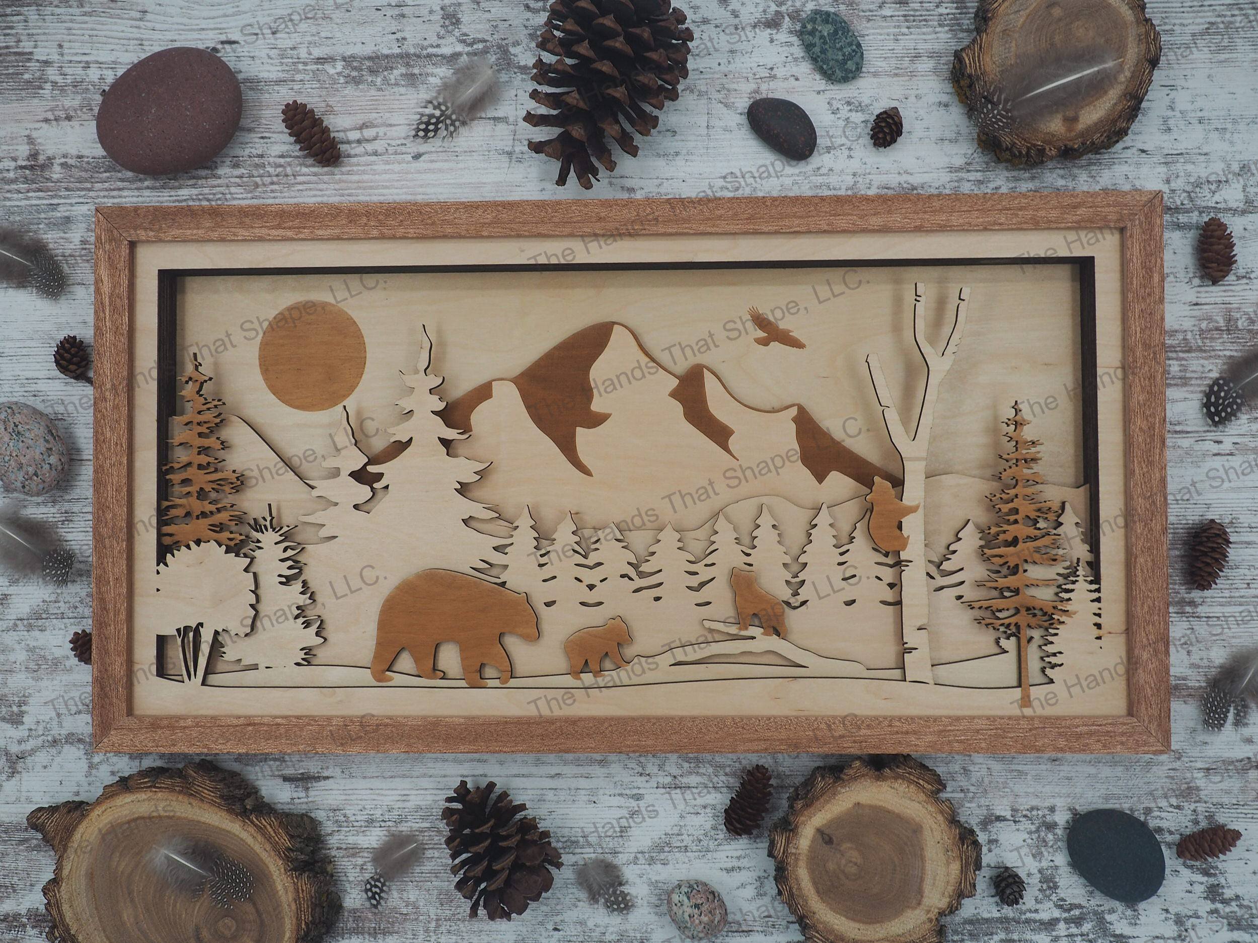 mama bear and cubs traveling through a forest with a majestic mountain range towering above