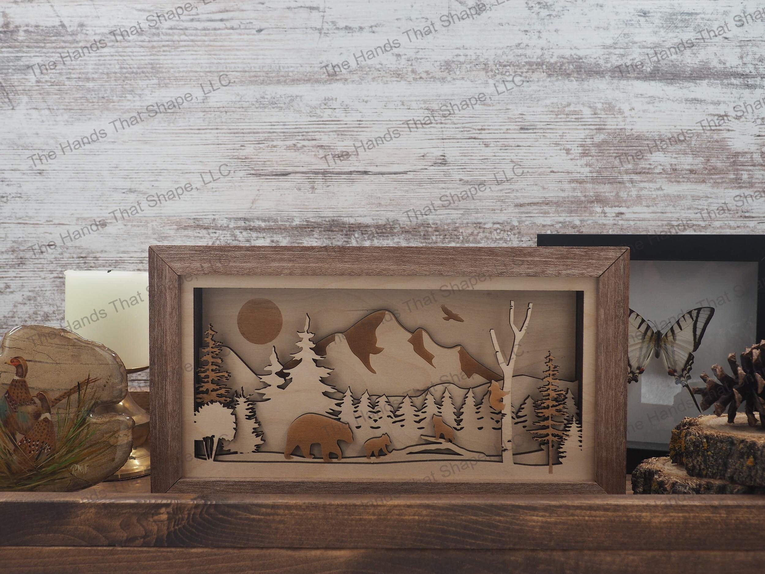 mama bear and cubs traveling through a forest with a majestic mountain range towering above
